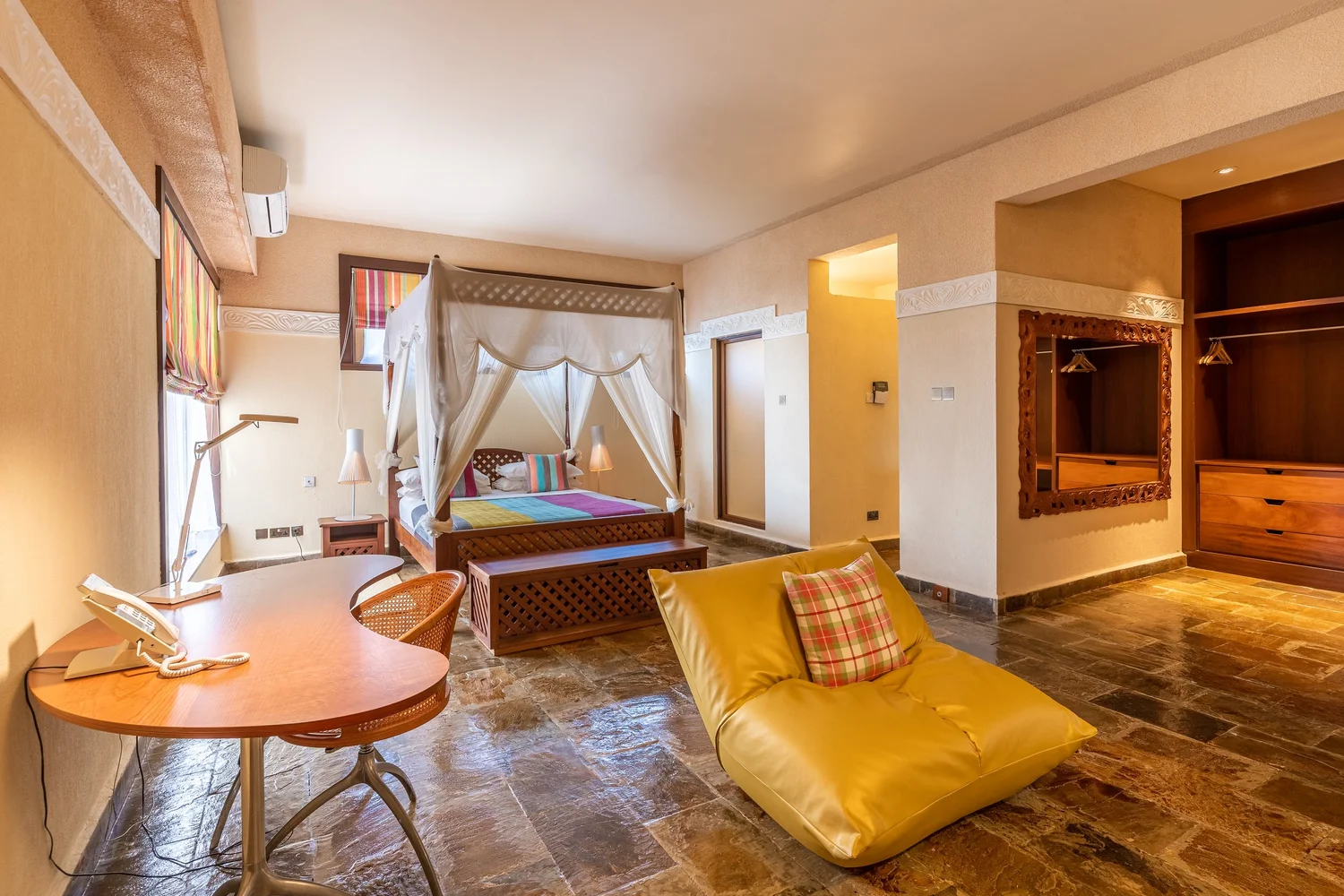 A light-filled Cocokinondo bedroom with a four-poster bed and natural finishes