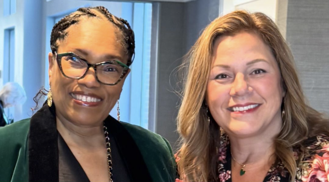 Cori Woolf and colleague at professional event, both women smiling at camera in business attire