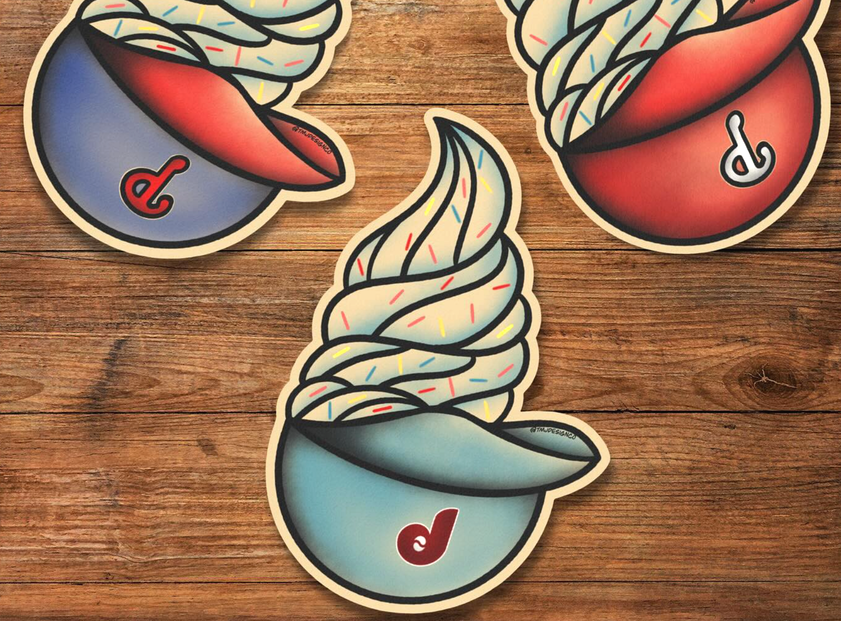 Three stickers featuring ice cream desserts on a wooden surface. Two stickers show ice cream in a bowl with colorful sprinkles and a spoon, with a red letter 'd' on the bowl. The third sticker depicts a soft serve ice cream swirl in a cup, with a similar red letter 'd'.