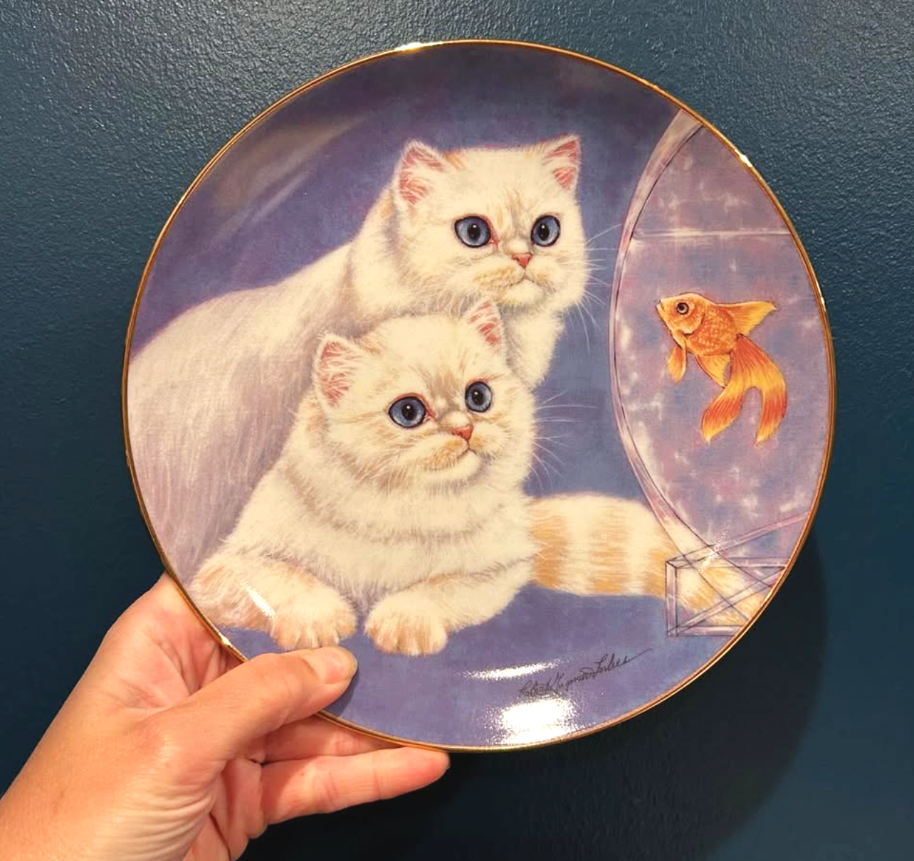 Decorative plate with a painting of two adorable kittens with large blue eyes watching a goldfish in a bowl.