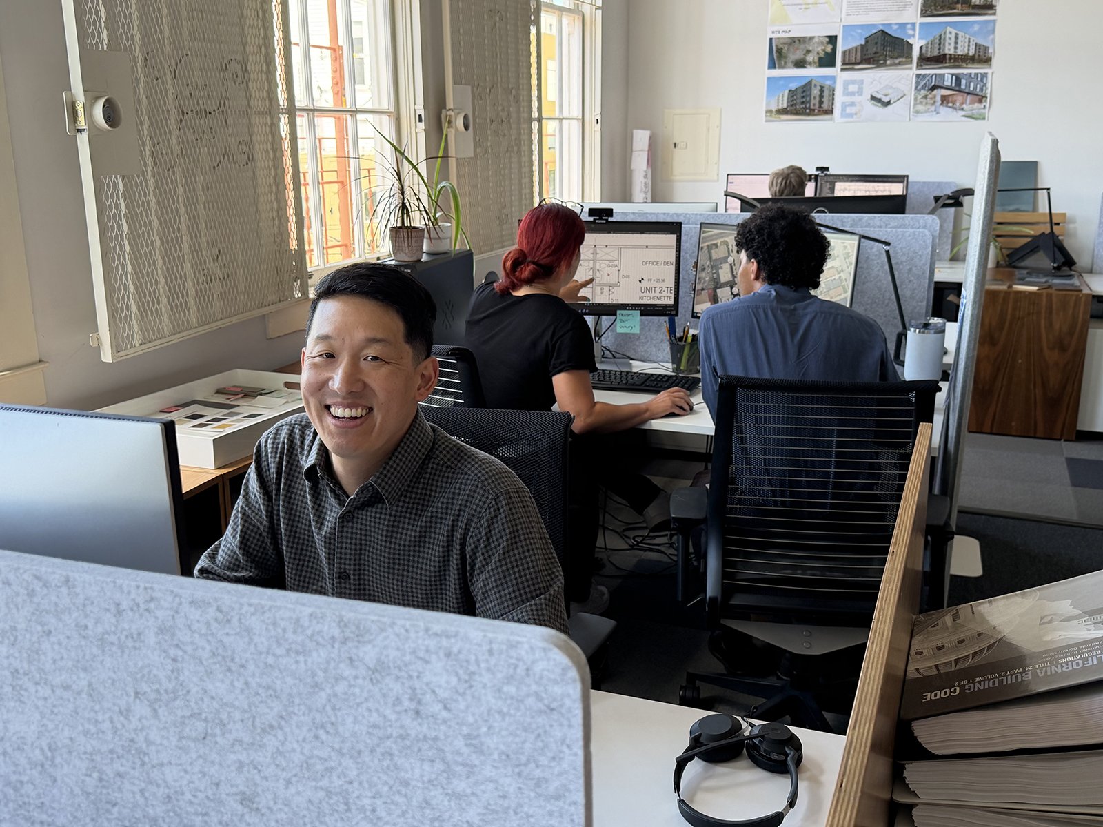 Y.A. studio team members working at computer stations in a bright office, with one staff member smiling toward the camera in the foreground