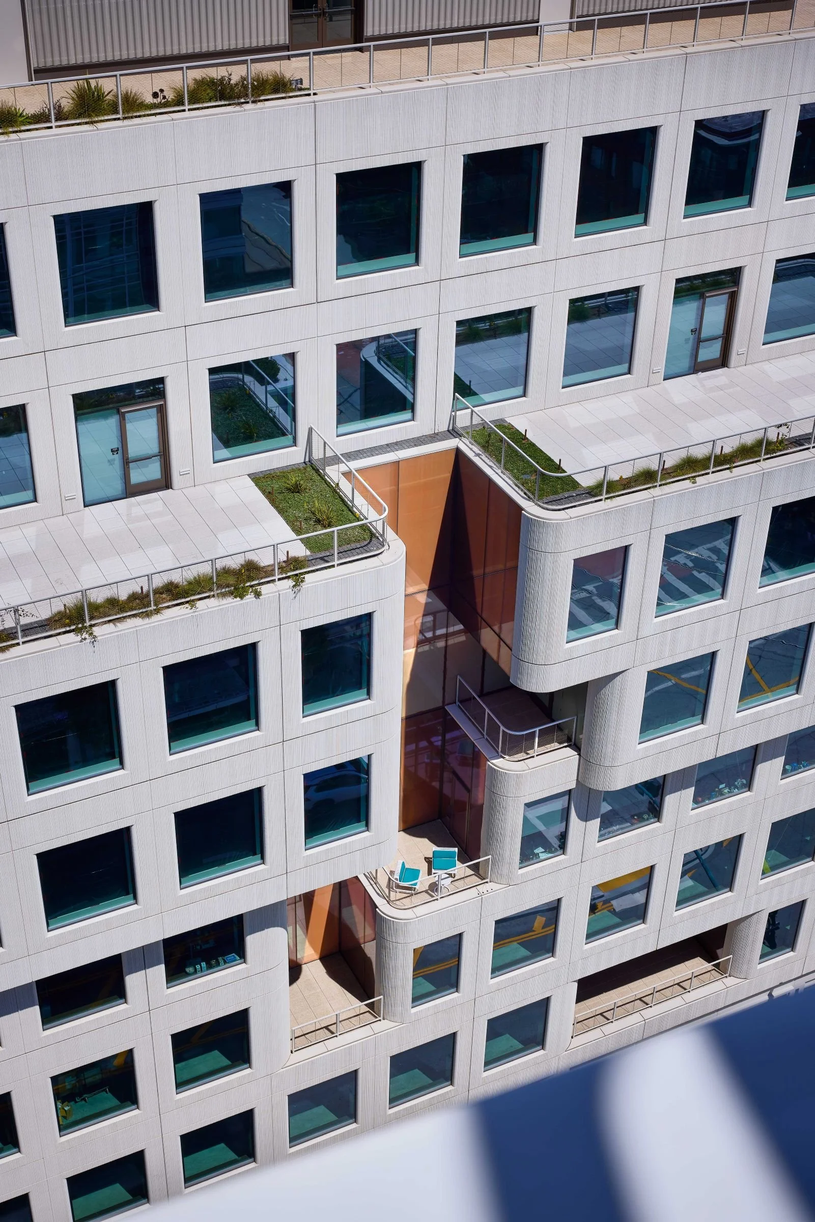 Mission Rock Block B facade detail with stepped terraces, planted roofs, and warm-toned recessed balconies.