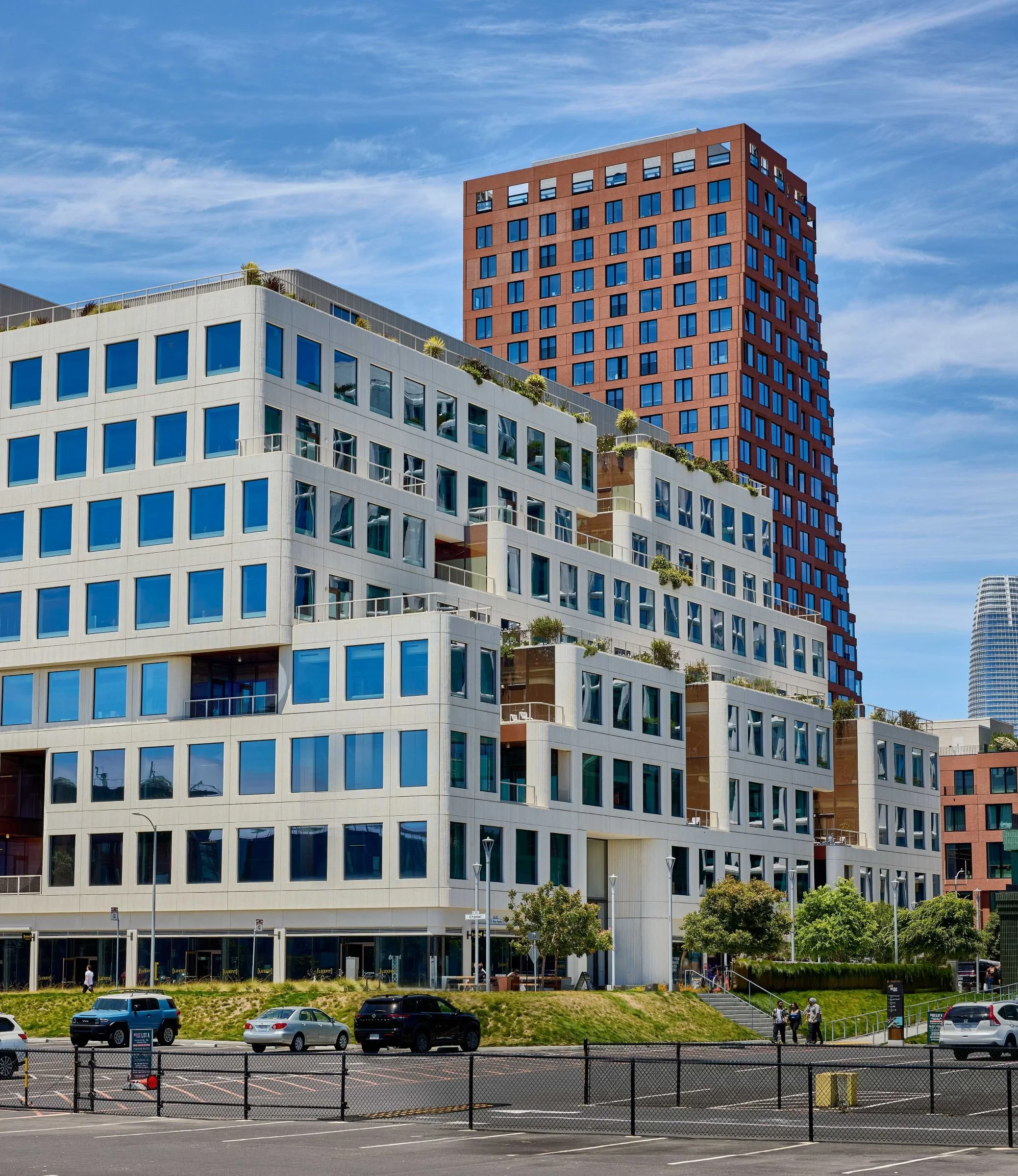 Mission Rock development with stepped white building and red tower under a blue sky.