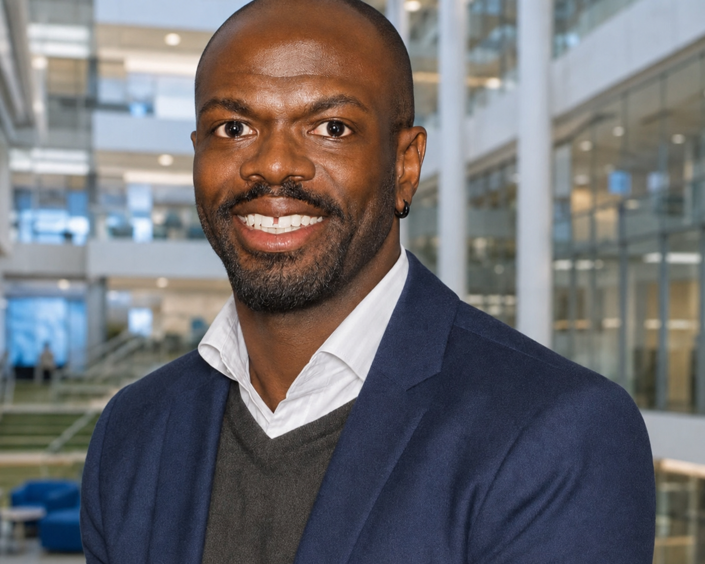Yannick Brookes in blue suit, white shirt, and blue tie, on a white background.
