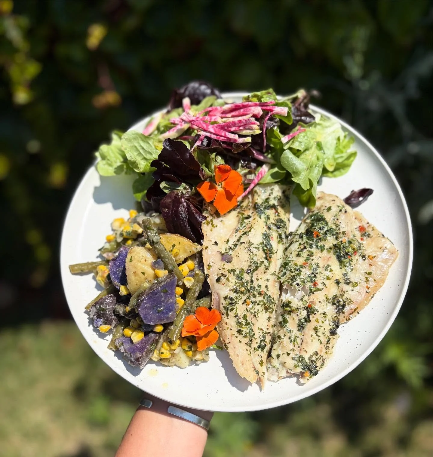 Soaking up the last bit of sunshine before the rain with branzino + herb salsa verde, rainbow potato salad, and a salad with lemon vinaigrette 🍋☀️