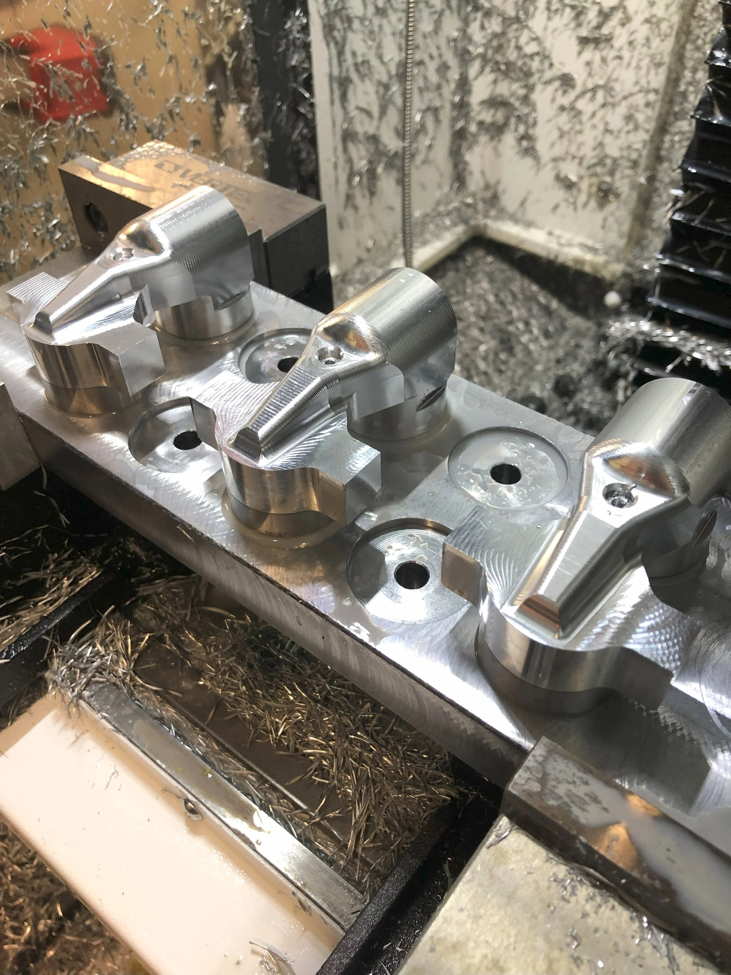 Close-up of metal components being machined, surrounded by metal shavings.