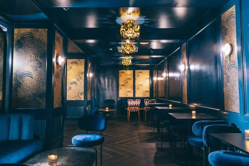 A long room of blue velvet seats and gold wall panels