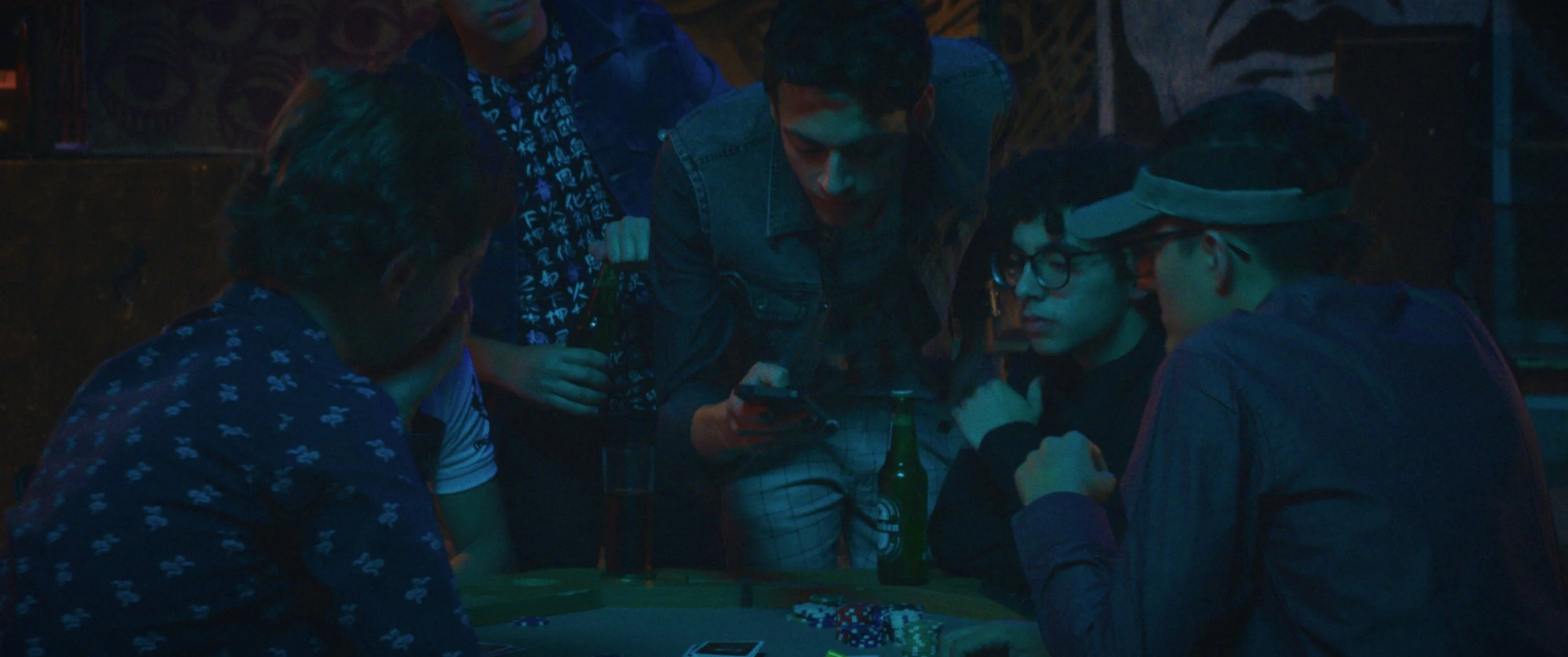 The Nation - Grupo de jóvenes jugando póker en un ambiente oscuro con iluminación tenue.