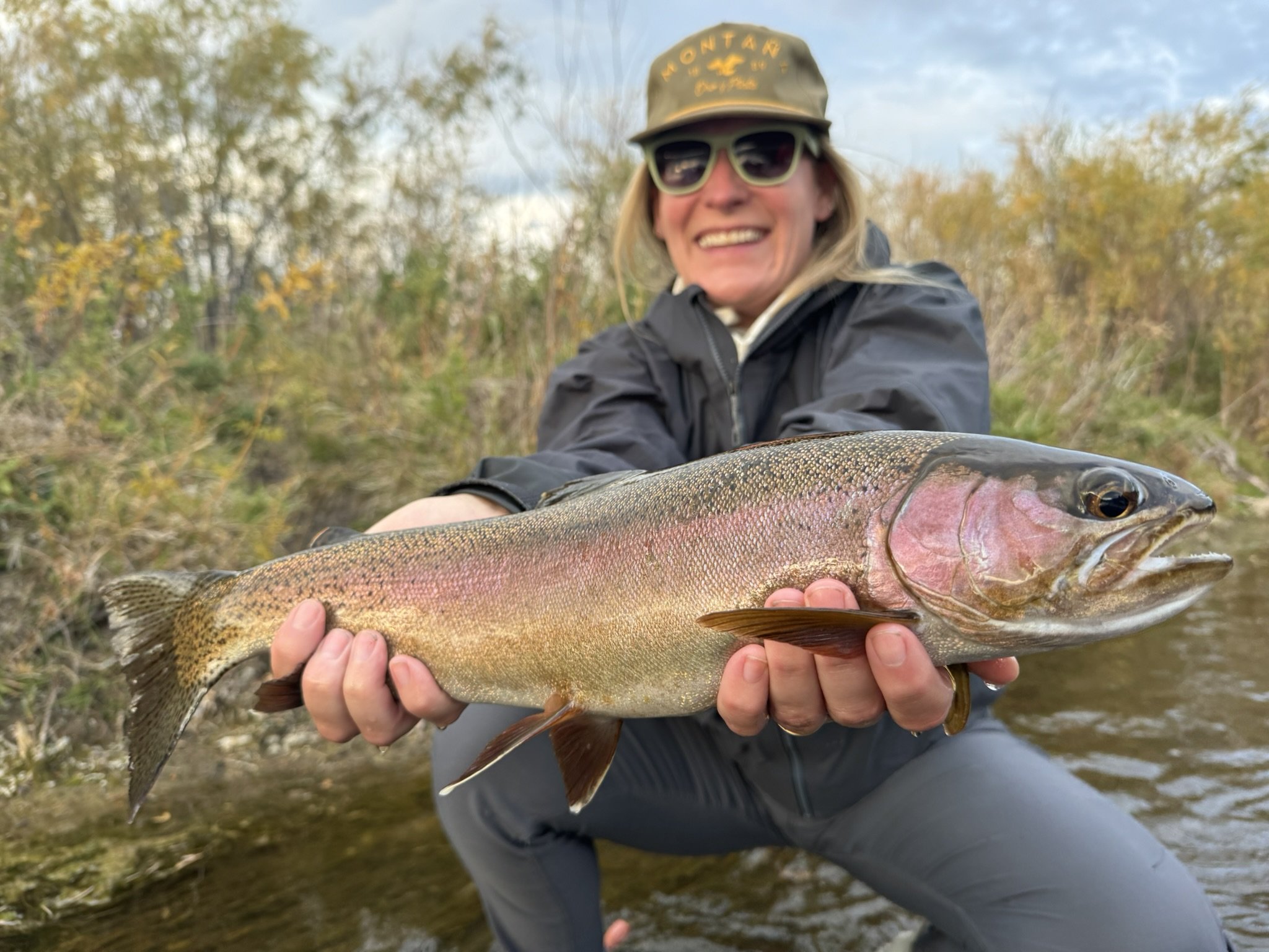 Angler with trophy rainbow trout in shallow water
