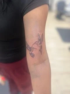 Tattoo of a hummingbird in flight on a person's upper arm