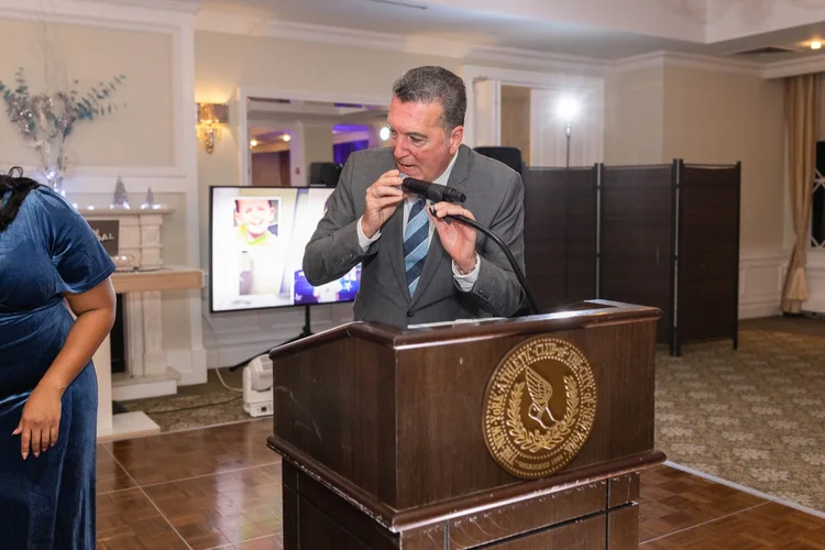 Man speaking into a microphone at a gala podium