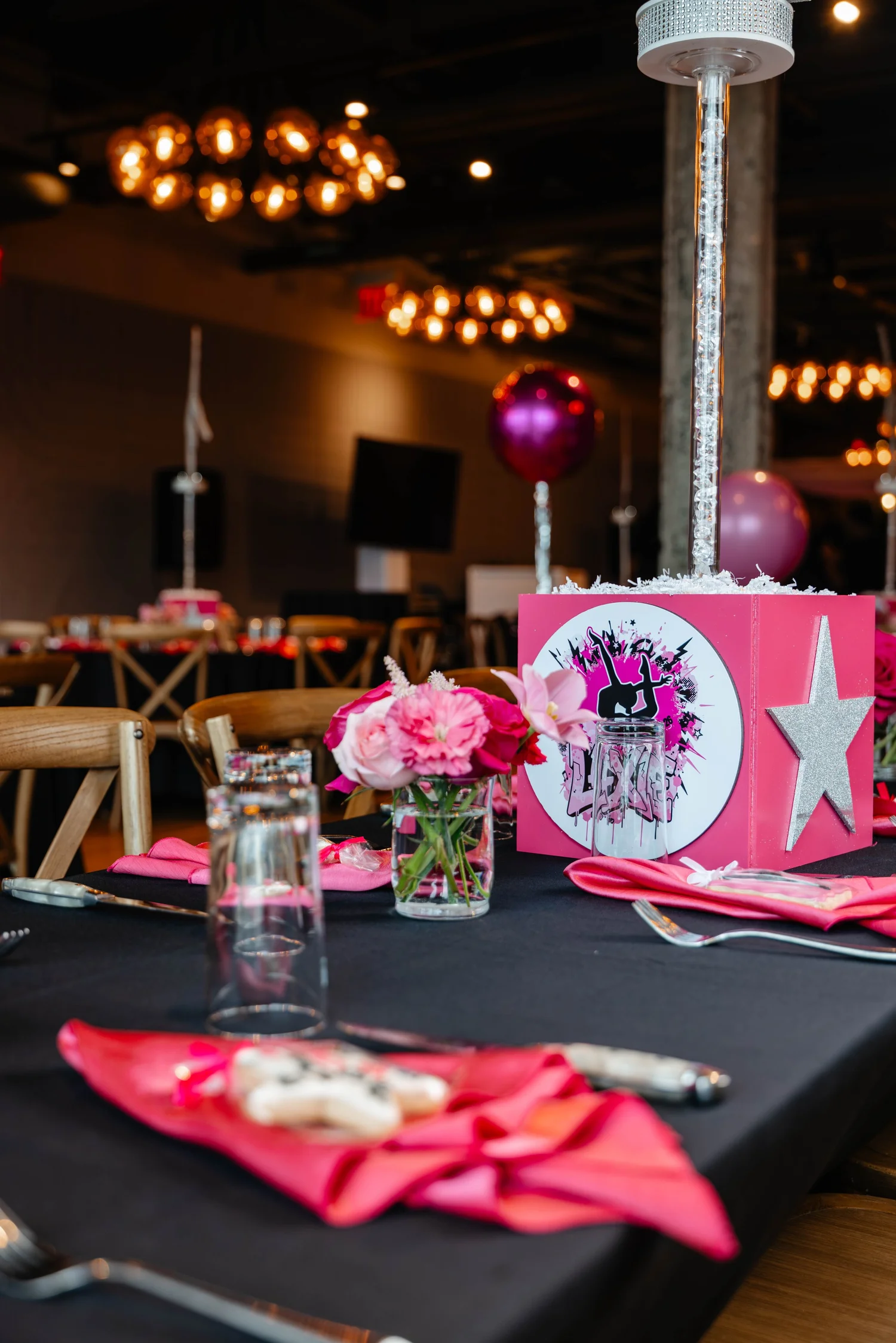 Custom pink bat mitzvah centerpiece beneath warm reception lighting