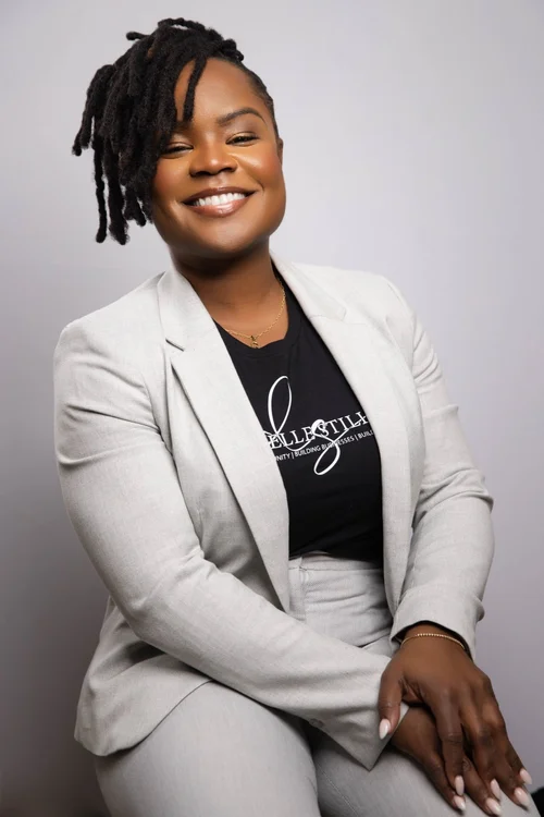 Portrait of a smiling woman in a light gray suit against a light gray backdrop