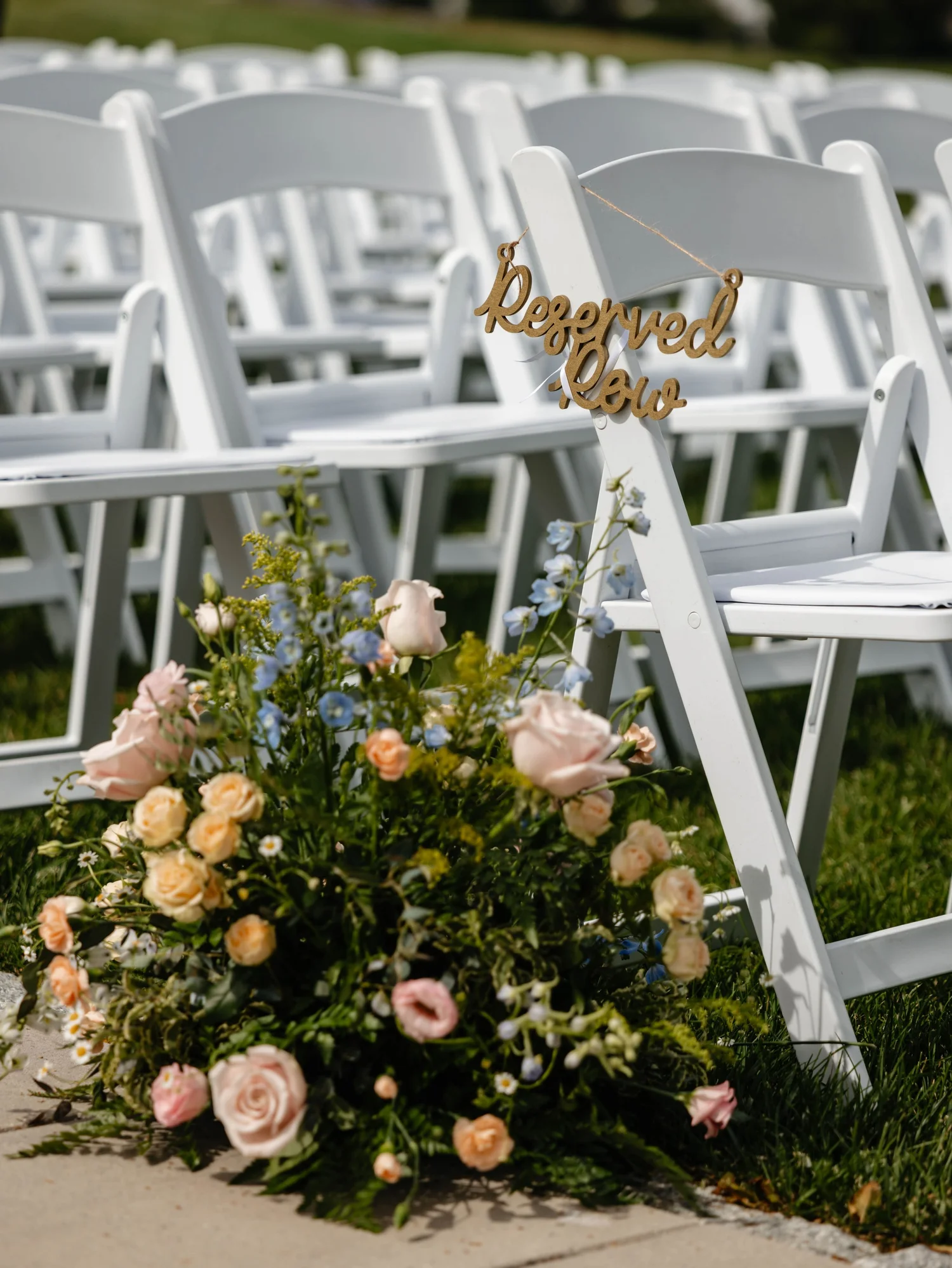 Reserved ceremony row beside soft pastel aisle flowers