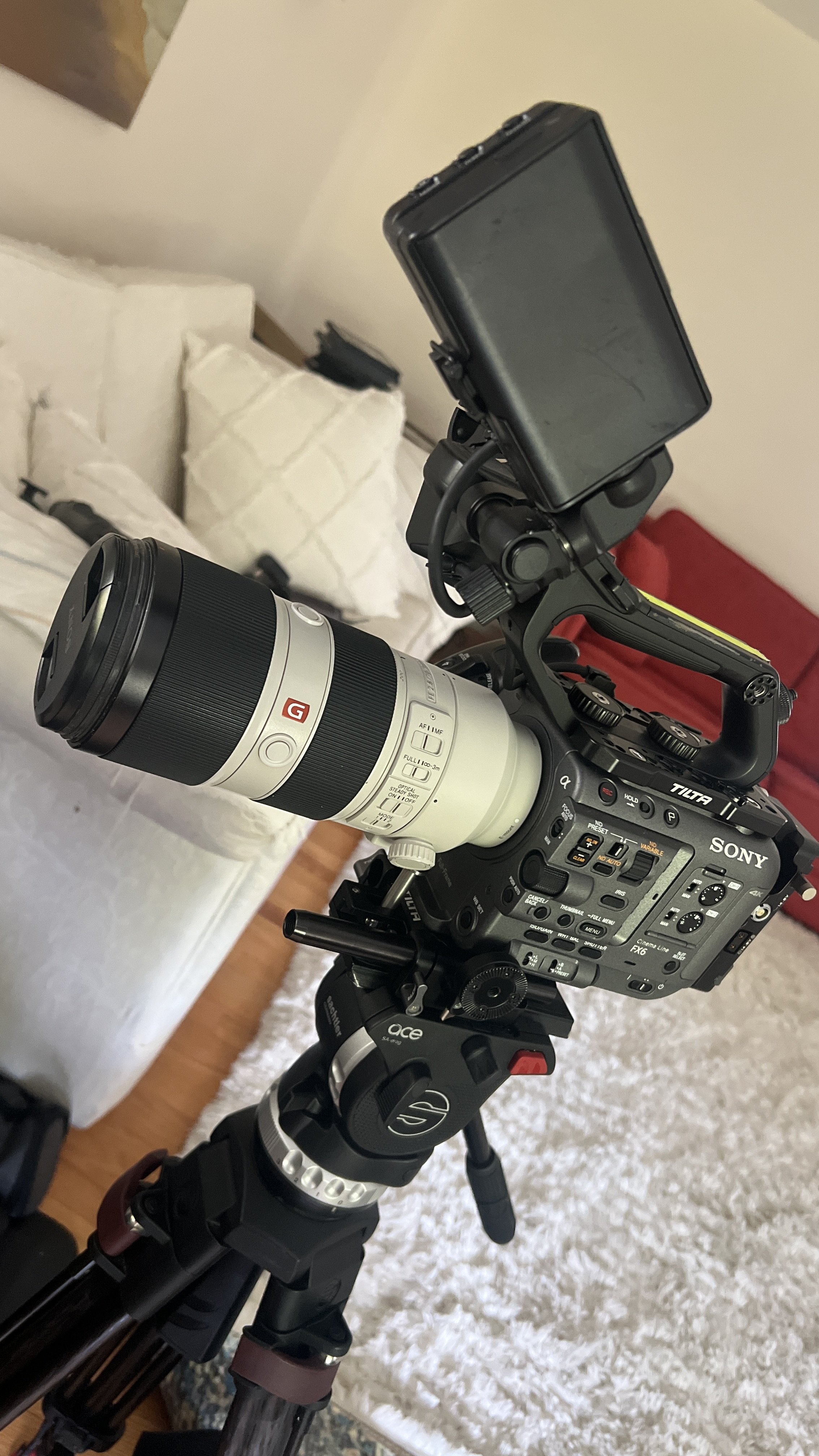 Photo of the FX6 atop a tripod with the top handle and a 70-200mm lens.