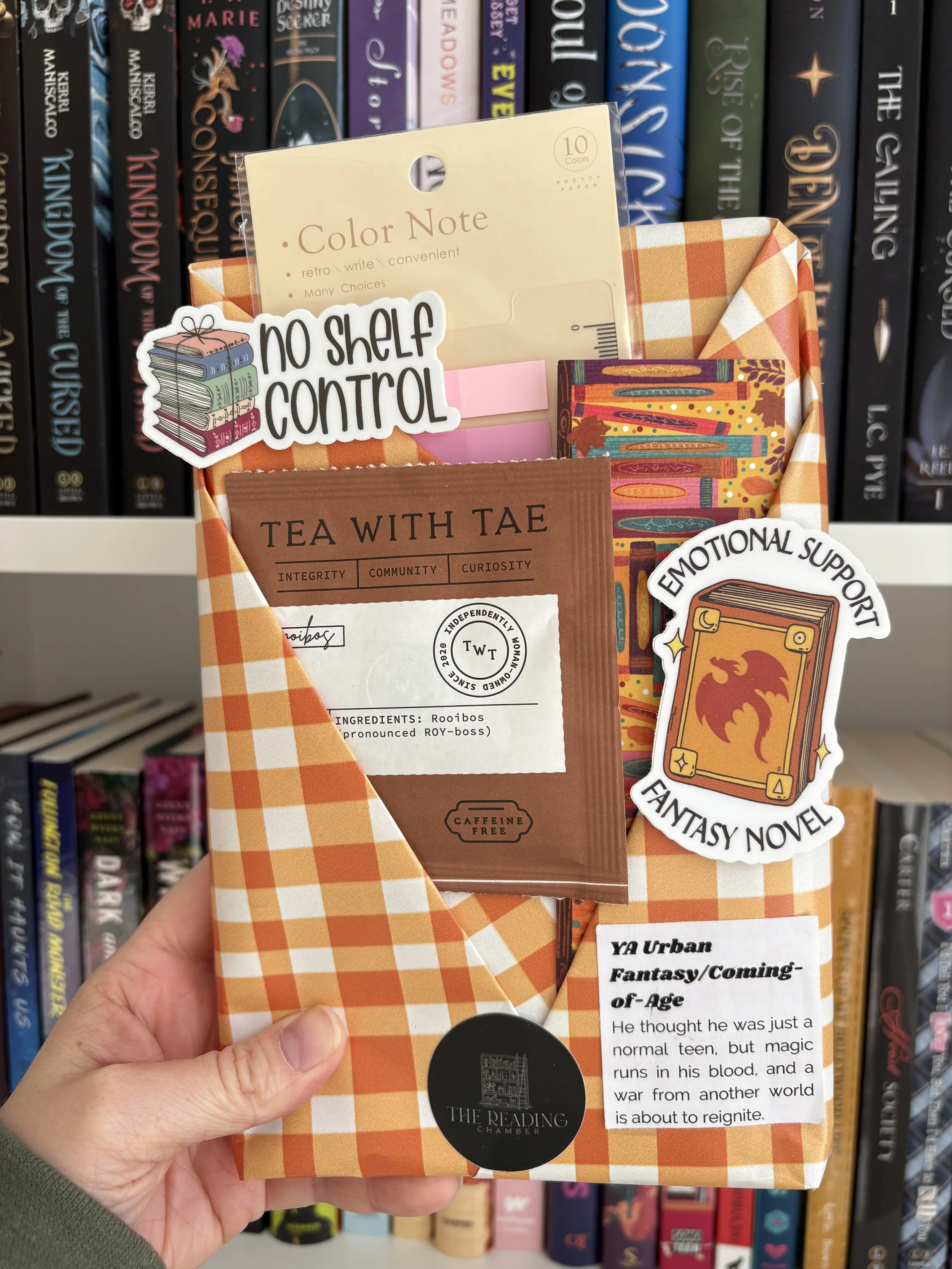 Blind date with a book featuring two stickers, annotation tabs, a bookmark, a packet of tea and an independently published YA book