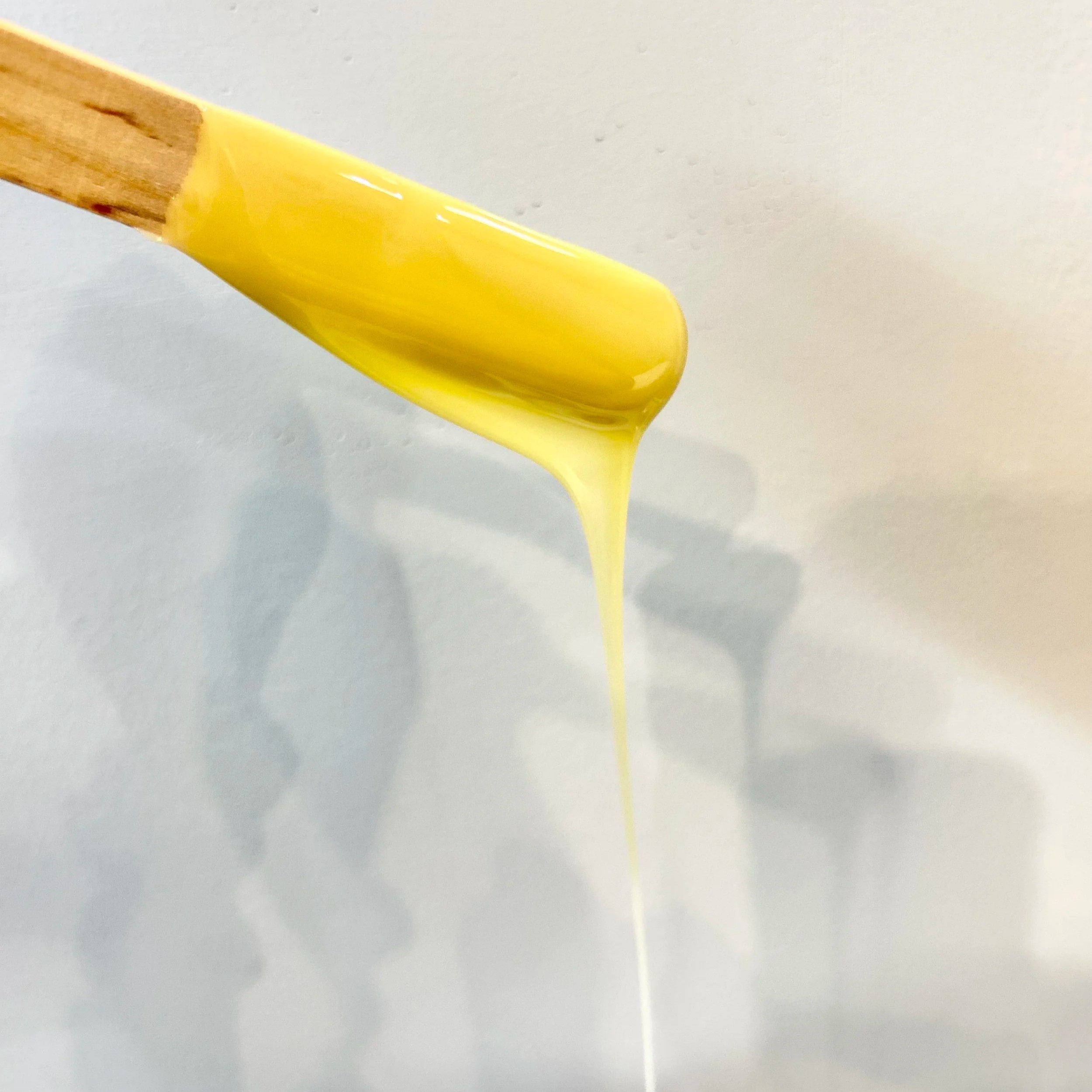wax stick dripping yellow wax with shadows in the background