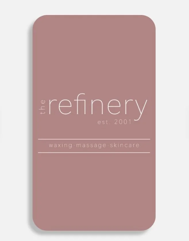 A pink rectangular card with rounded corners displaying the logo of 'the refinery,' established in 2001, offering waxing, massage, and skincare services.