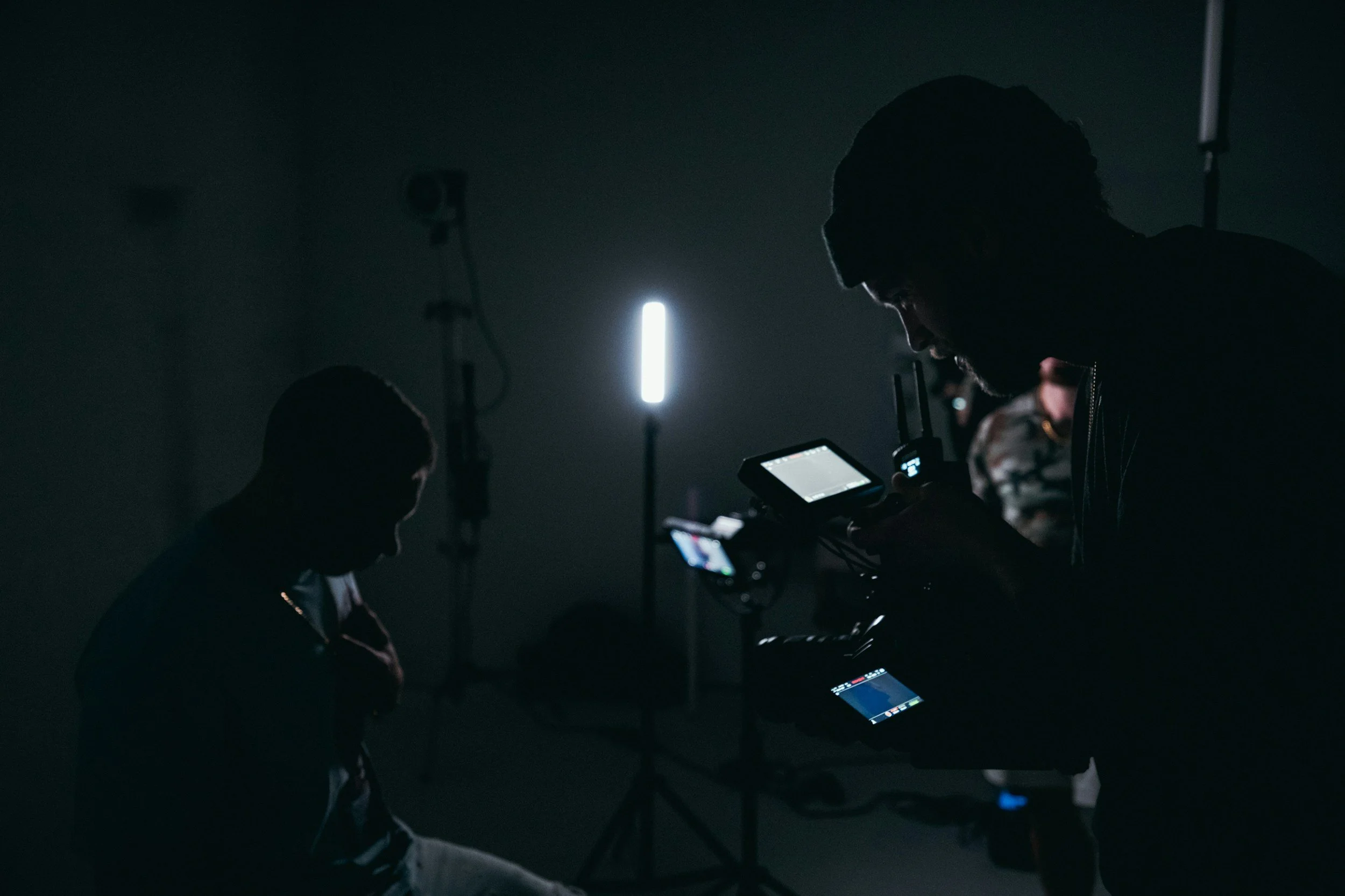 Personas en un estudio oscuro con cámaras y luces profesionales.