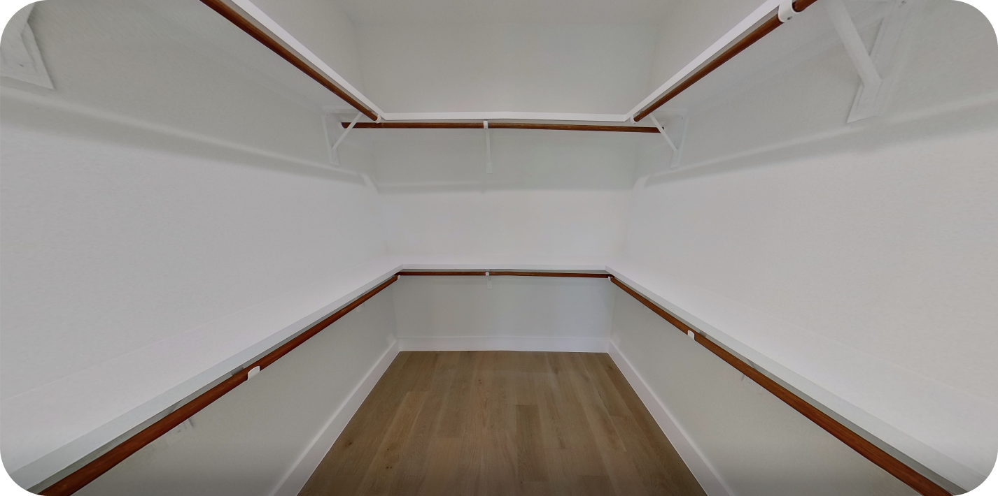Before photo of empty walk-in closet with white walls, wooden floor, and hanging rods on both sides.