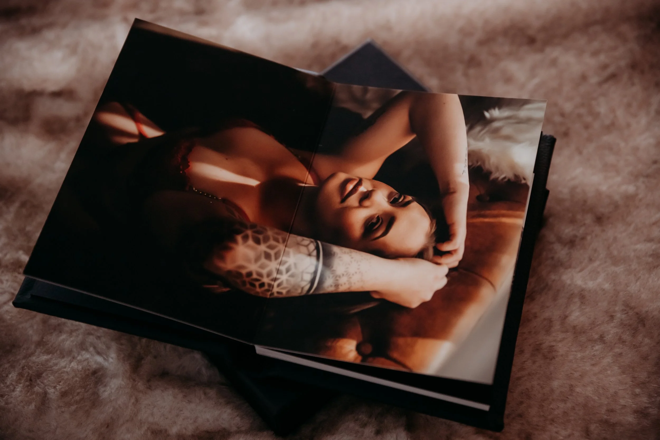 Open photo album with a cover photo of a woman with long hair lying on a bed, wearing a black lace top, on a soft, textured surface.