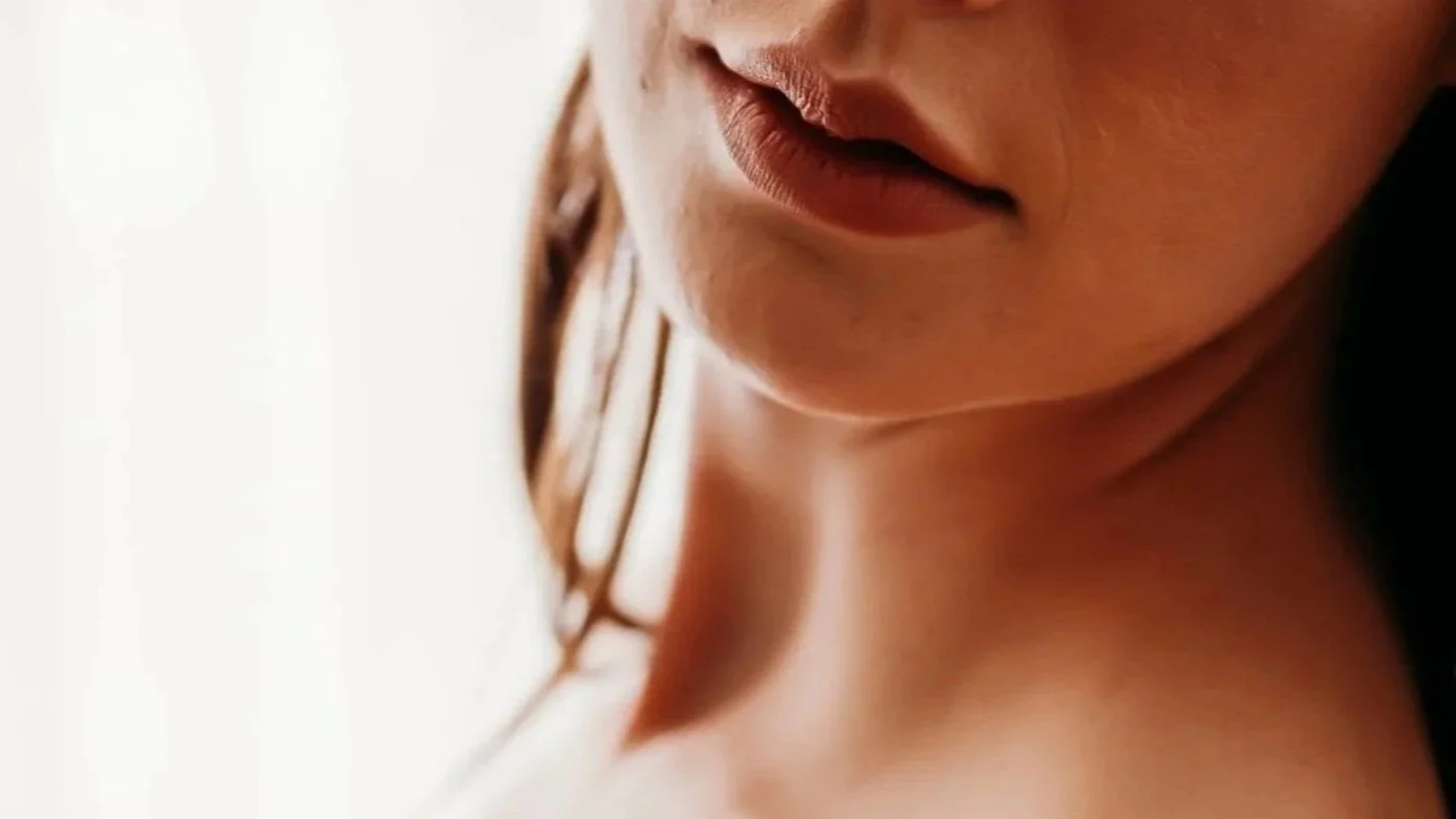 Close-up of a woman's face and shoulder, with a focus on her lips and skin.