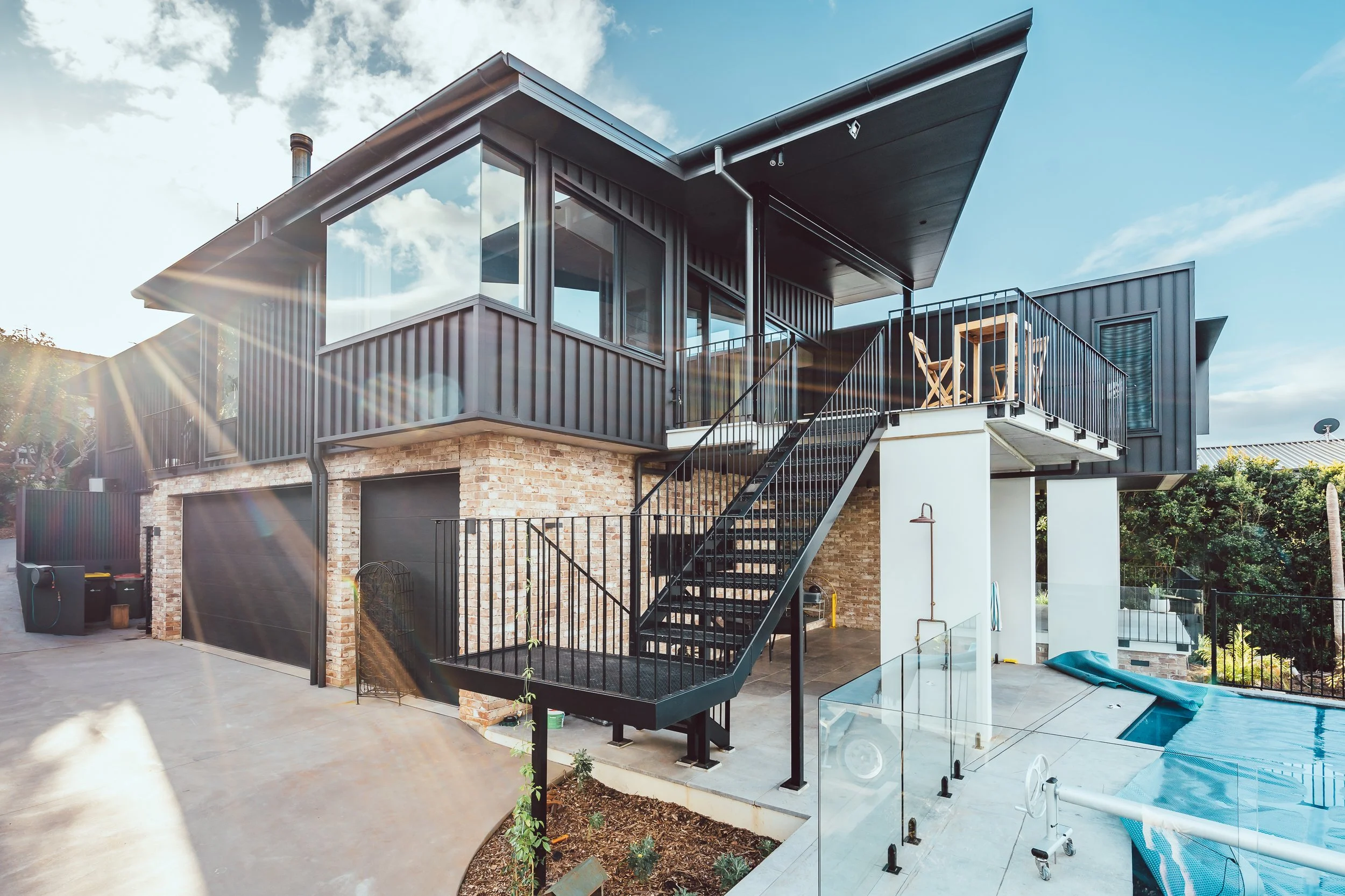 Luxury architecturally-designed residential project in Port Macquarie includes recycled brick, black metal and timber exterior, and luxury pool surrounded by beautifully landscaped garden.