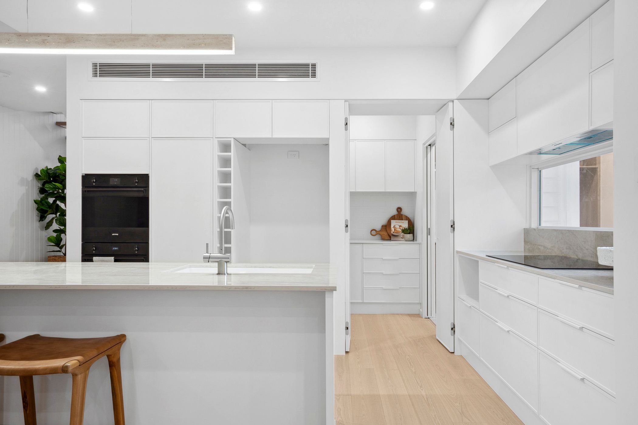 Custom built duplex project in Port Macquarie features modern white kitchen with large island, stone bench tops, and walk in butler's pantry.