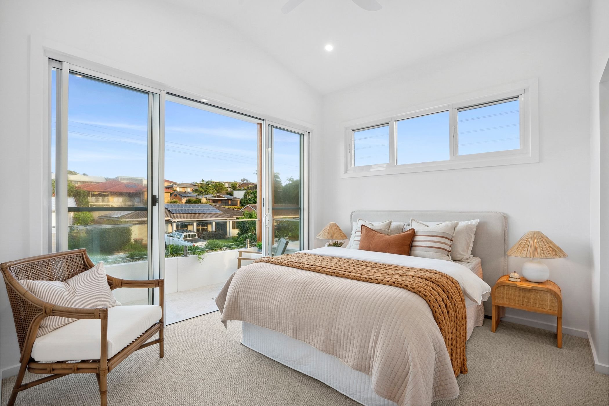 Custom designed duplex project in Port Macquarie features bright bedroom with large sliding glass door onto balcony.