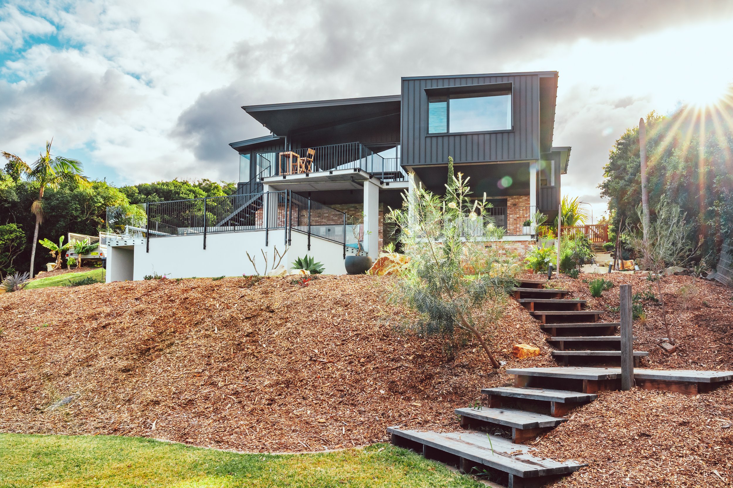 Luxury architecturally-designed residential project in Port Macquarie includes recycled brick, black metal and timber exterior surrounded by beautifully landscaped garden.