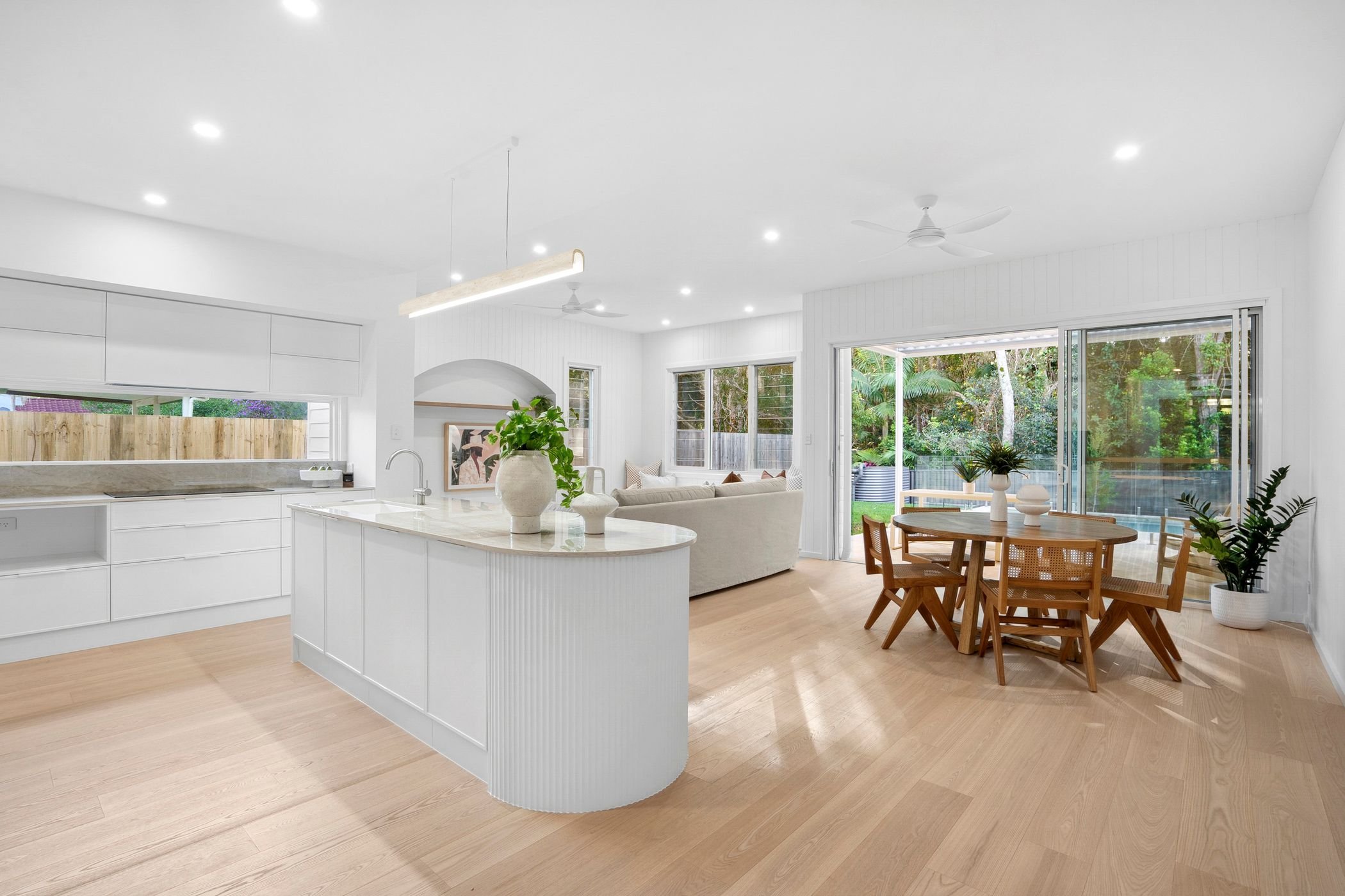 Boutique duplex project in Port Macquarie features modern open-plan kitchen, dining and living area with large windows and glass sliding doors out to alfresco area and pool.