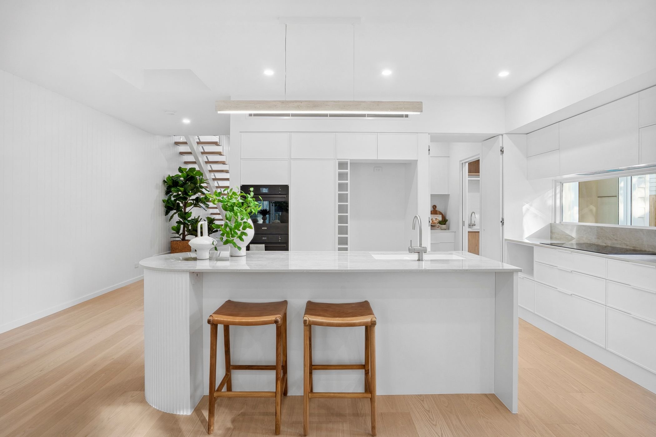 Boutique duplex project in Port Macquarie features modern white kitchen with large island, stone bench tops, and walk in butler's pantry.