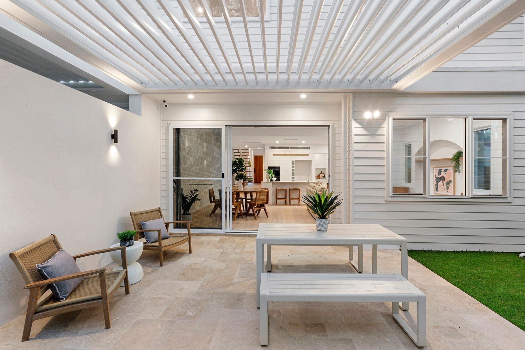 Boutique duplex project in Port Macquarie features modern open-plan kitchen, dining and living area with large windows and glass sliding doors out to alfresco area and pool.
