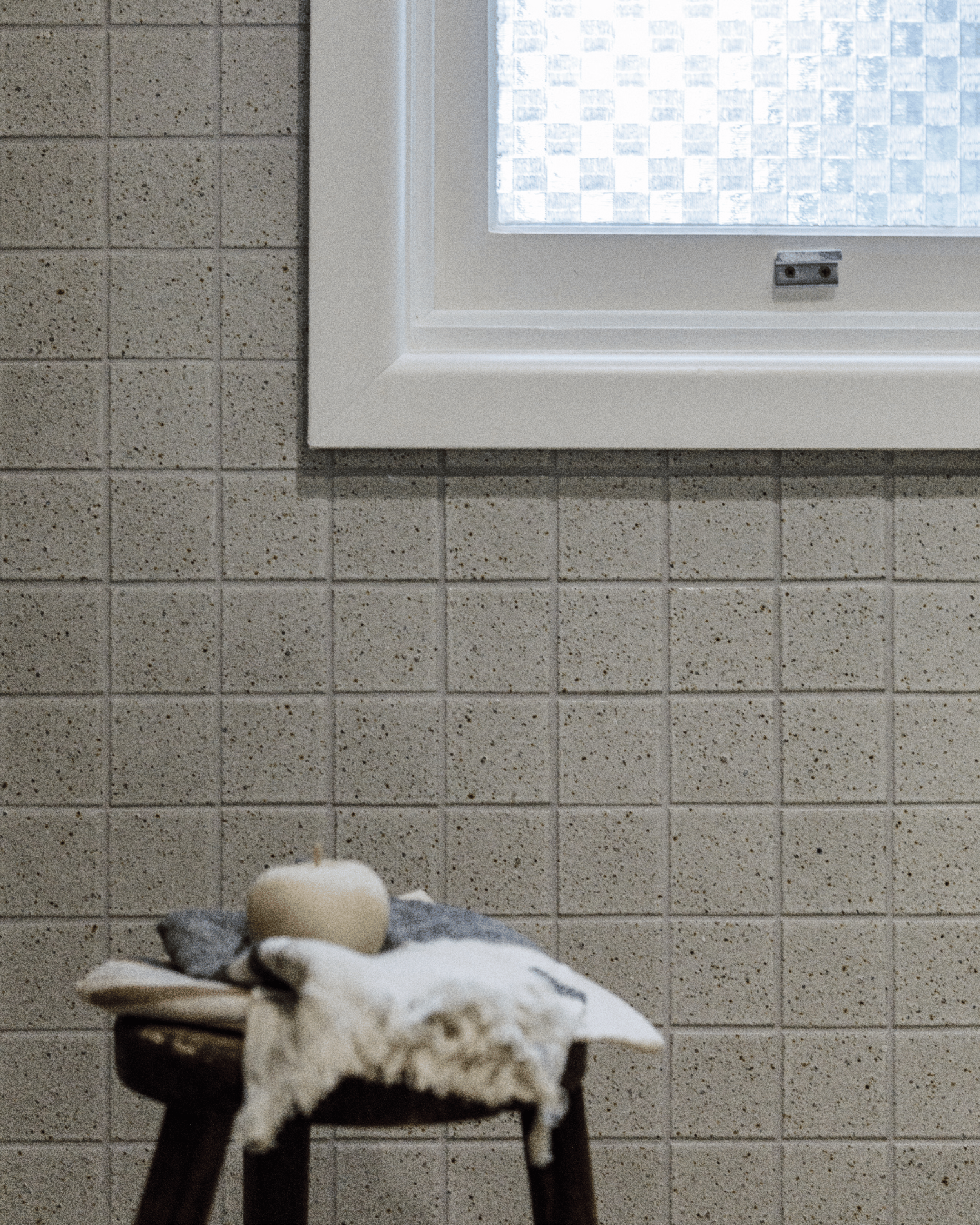 Original checkerboard glass window framed by textured ceramic wall tiles.
