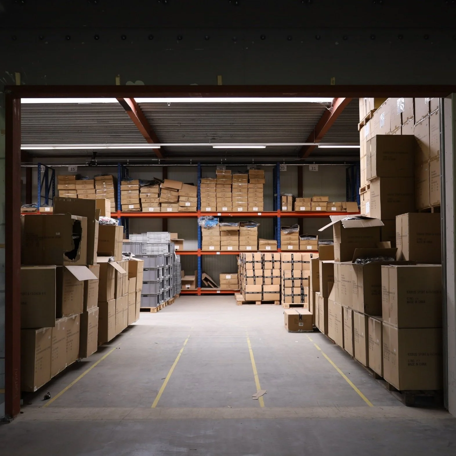 Binnen een magazijn met gestapelde dozen en pallets