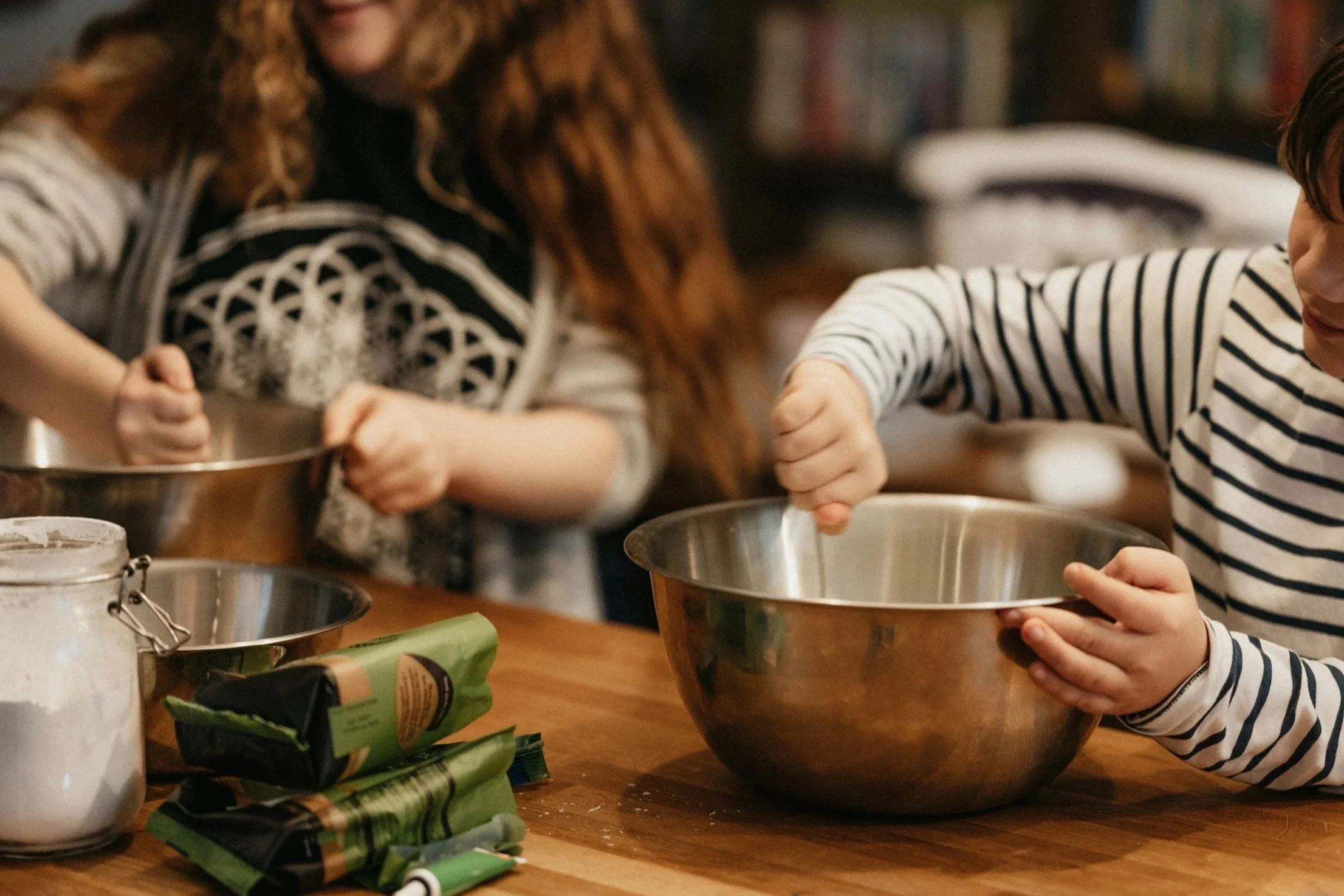 Kinder beim Backen in der Küche, sie rühren in großen Edelstahltöpfen