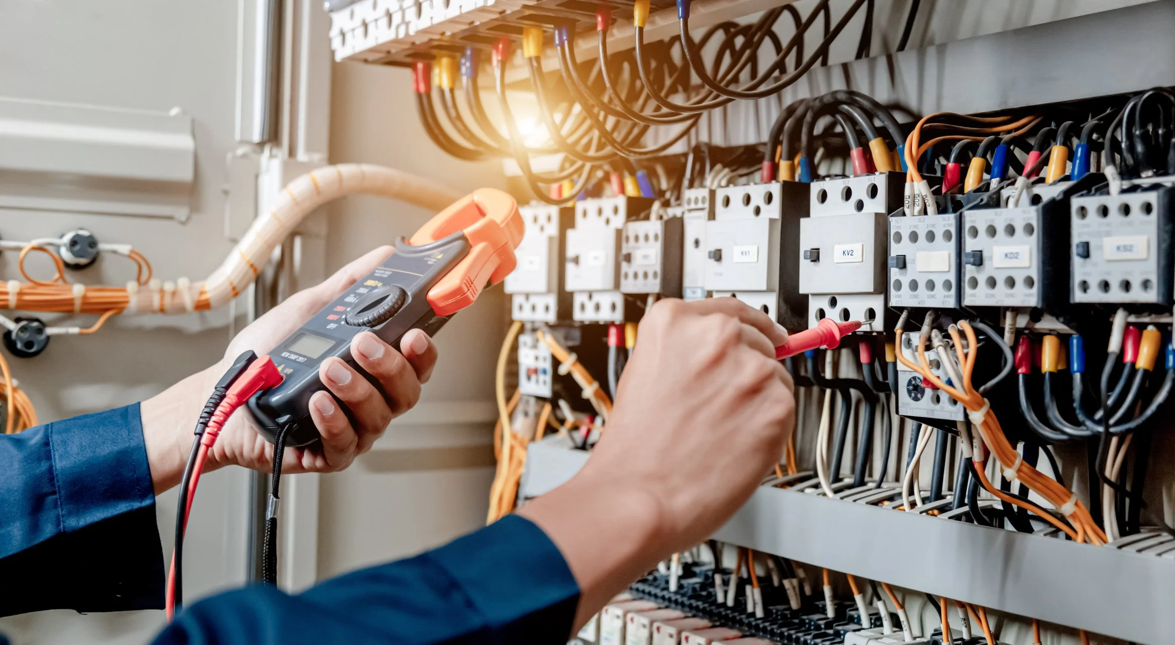 A Journeyman Electrician testing electrical panels with a multimeter, wiring and circuit breakers in an electrical control panel.