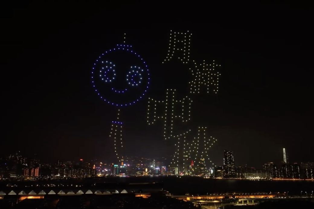 Light display in the night sky showing a smiley face and Chinese characters.