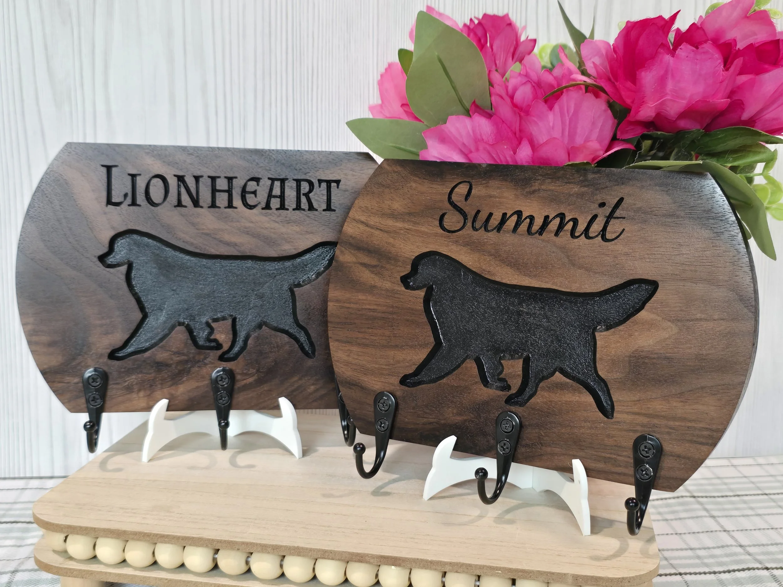 Decorative leash holders with Bernese Mountain Dog silhouettes and text reading 'LIONHEART  and Summit' displayed on a wooden board.