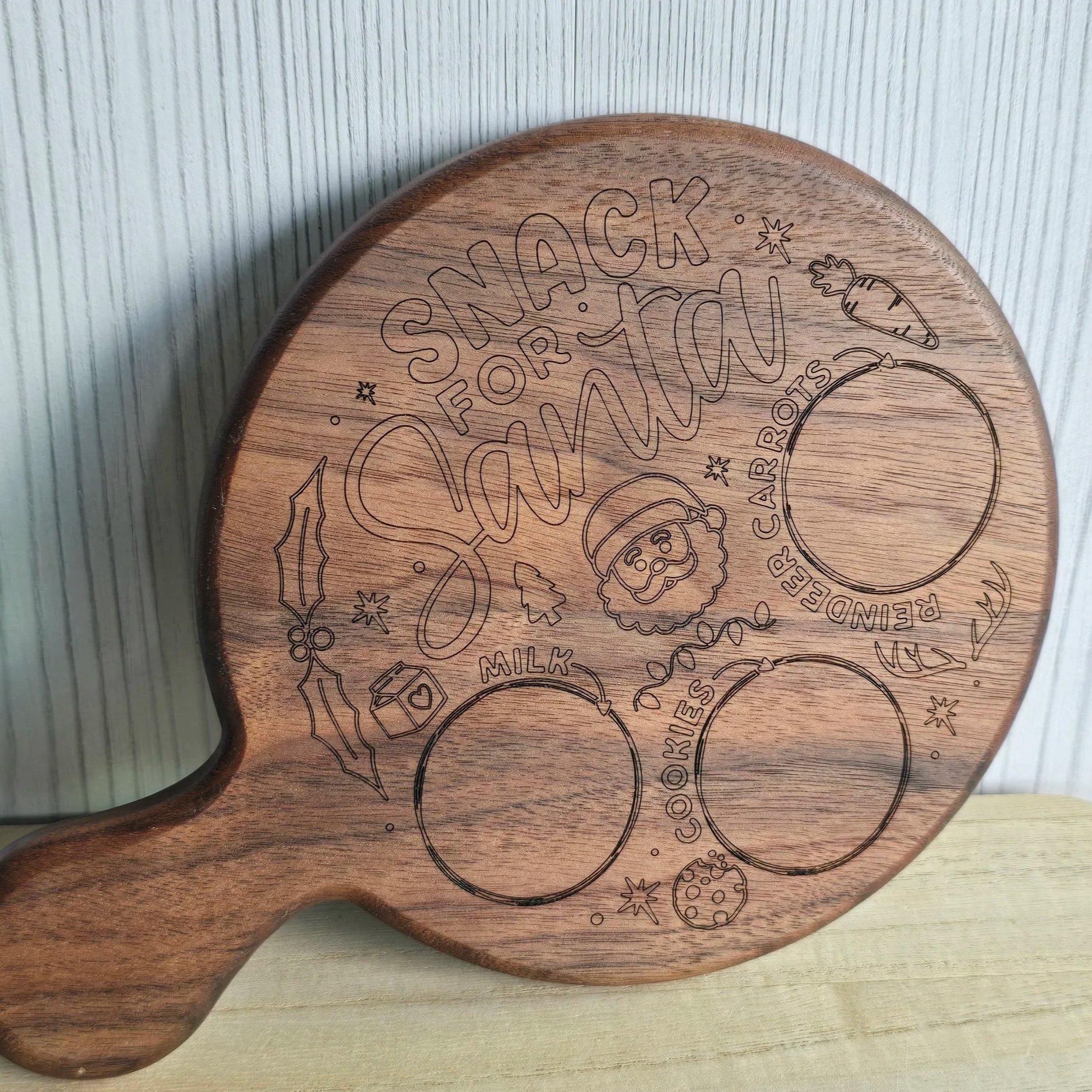 A wooden cutting board with engraved holiday-themed illustrations and text, featuring Christmas cookies, a cupcake, holly, a Christmas tree, and the phrase "Sleigh Forfa Yard 2023".