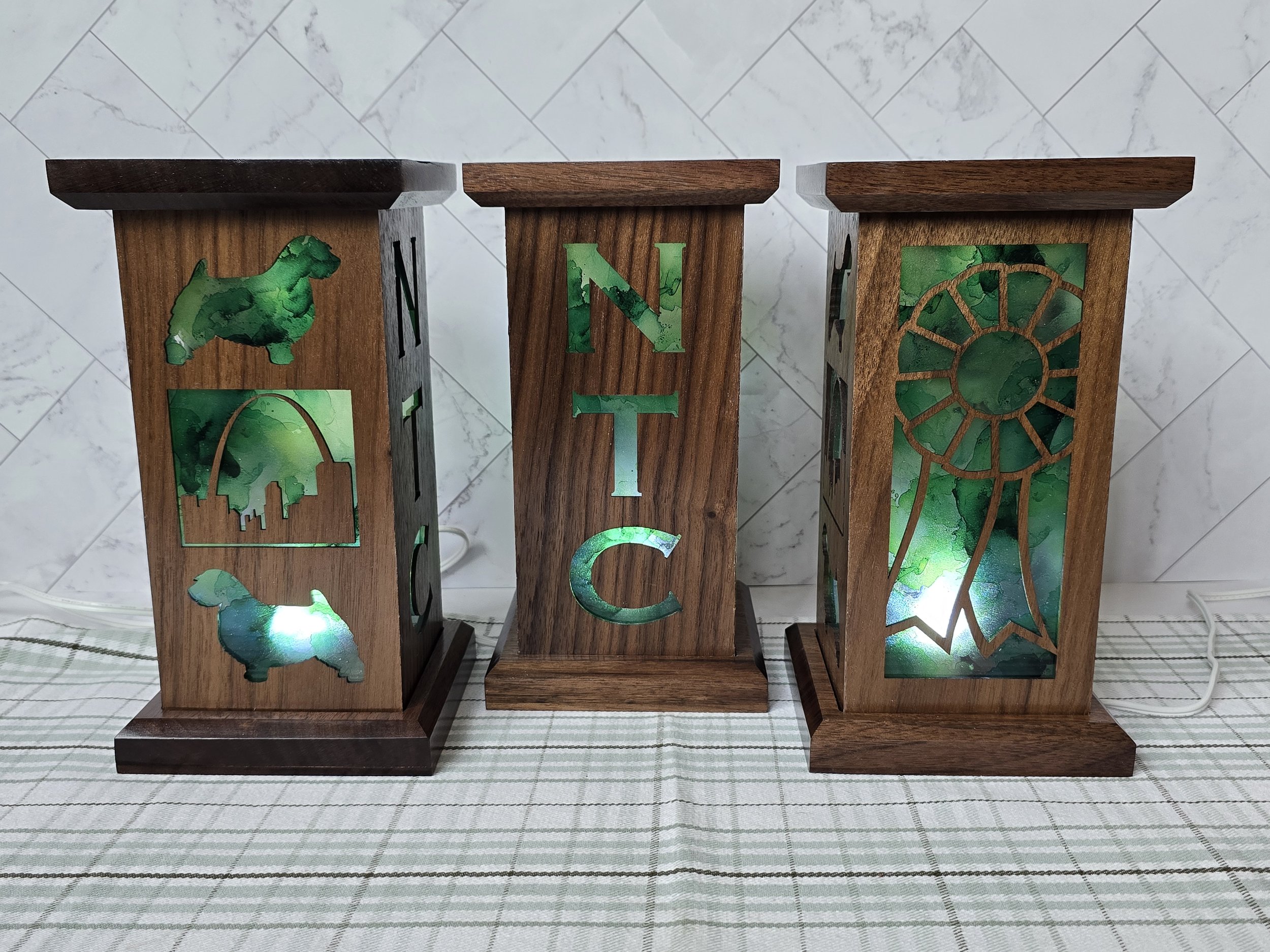 Three walnut lanterns with NTC lettering, Norwich Terrier cutouts, the Gateway Arch and a rosette