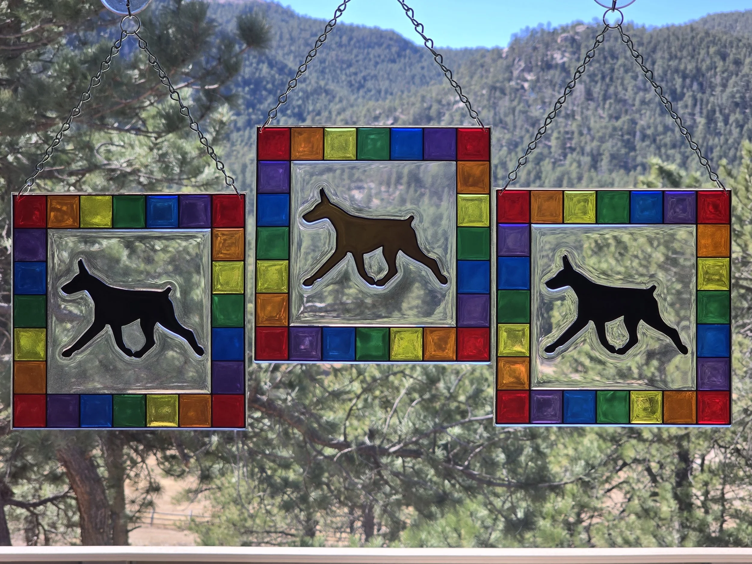 Three square resin suncatchers with rainbow checkered borders and Doberman Pinscher silhouettes