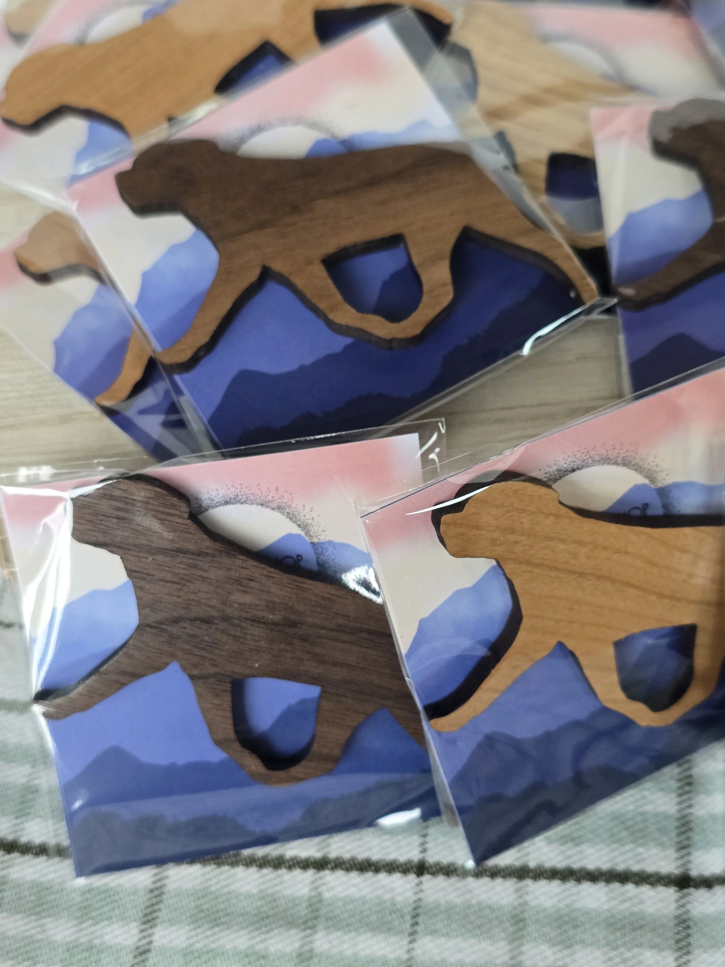 Wooden Rottweiler shaped magnets in cellophane packaging with mountain landscape design backer.