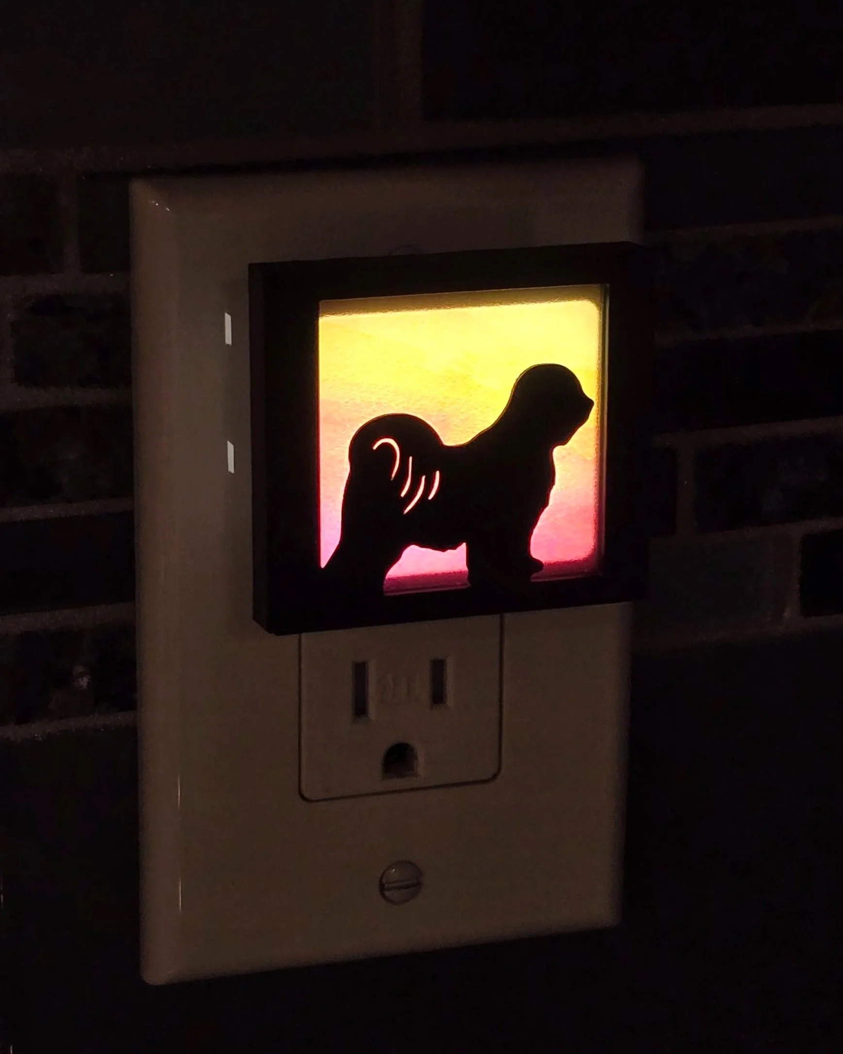 Nightlight lit in a dark room, Tibetan Terrier cover over a sunset orange acrylic panel