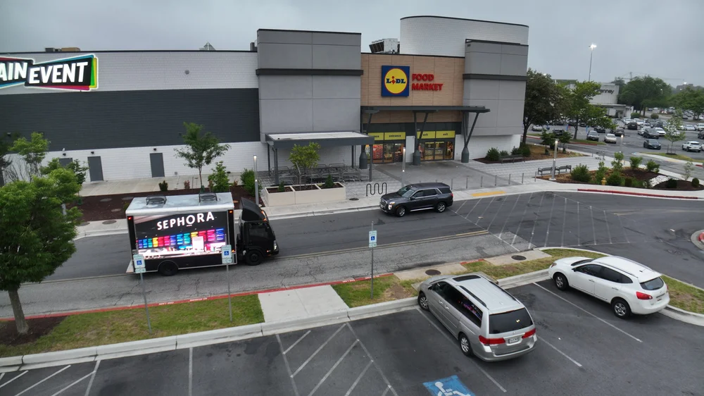LED billboard truck driving past a shopping plaza