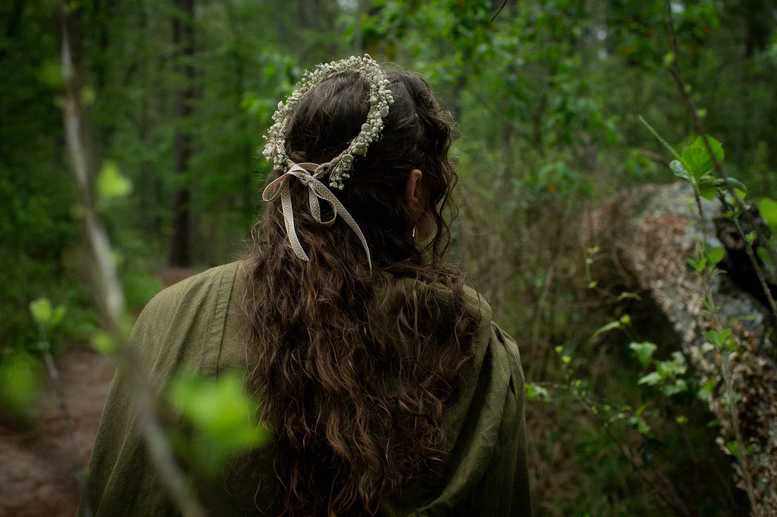 Young woman wearing flower crown walking through a forest in Huntsville, Texas