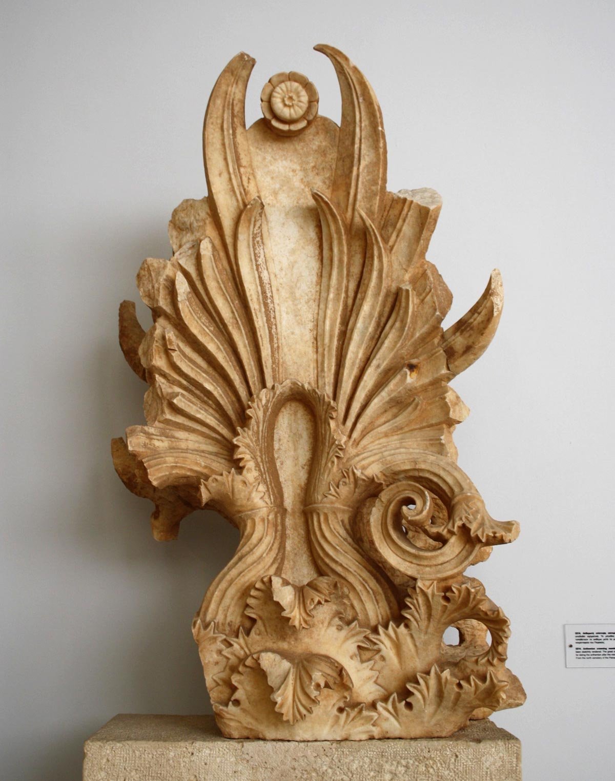 Carved marble anthemion with curling leaves and tall central palmette, rising like a stone flame from the top of a funerary stele.