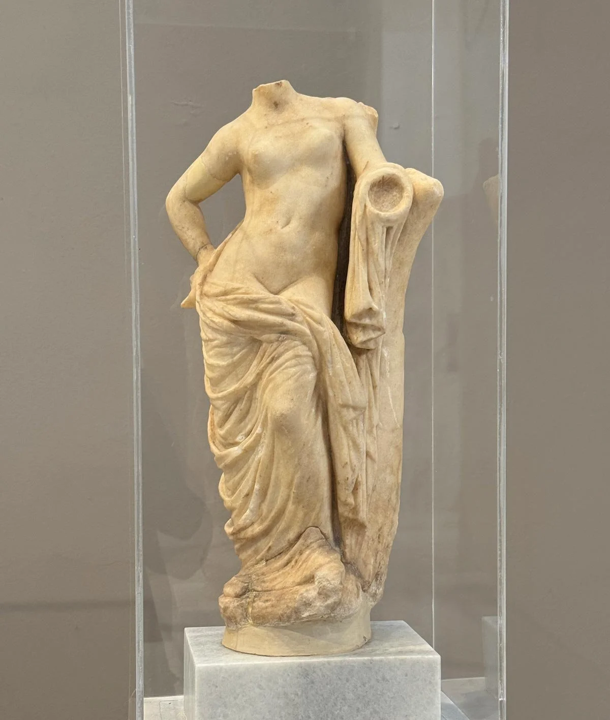 Small marble Aphrodite/Venus-type statuette fragment with drapery at the hips and missing head/arms.