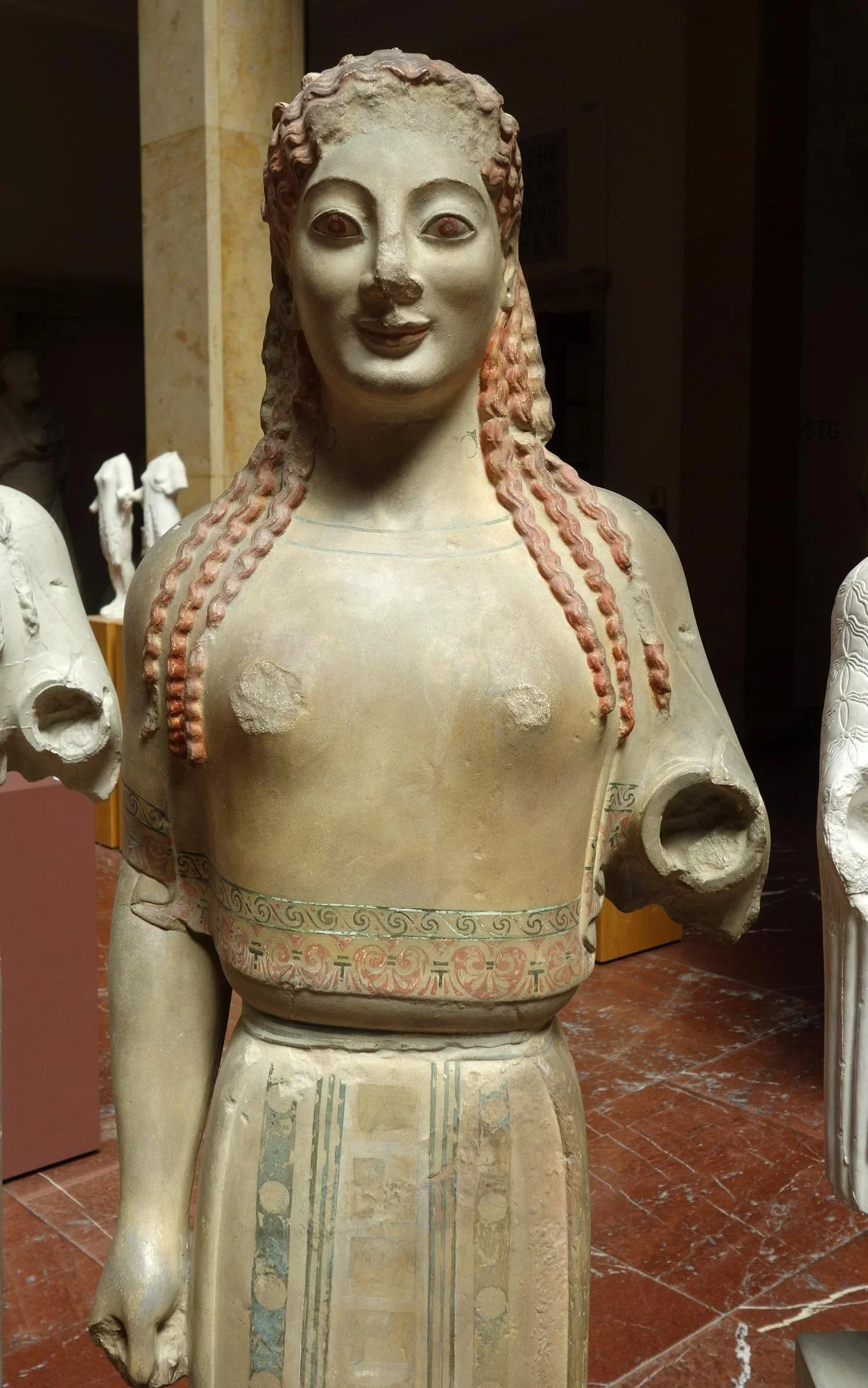 Painted plaster cast of Acropolis Kore 679, with red dress, patterned borders and vivid details reimagining the statue’s lost colours.