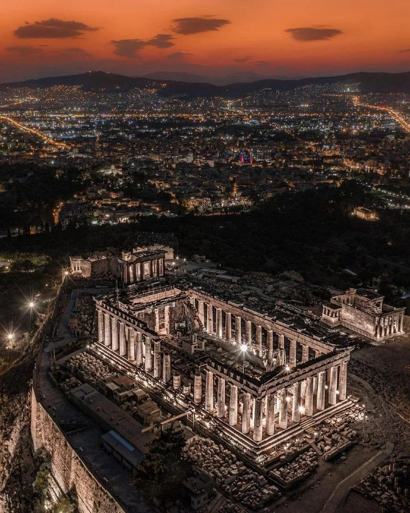 Night view of the Acropolis lit up above Athens, with the city glowing in the distance.